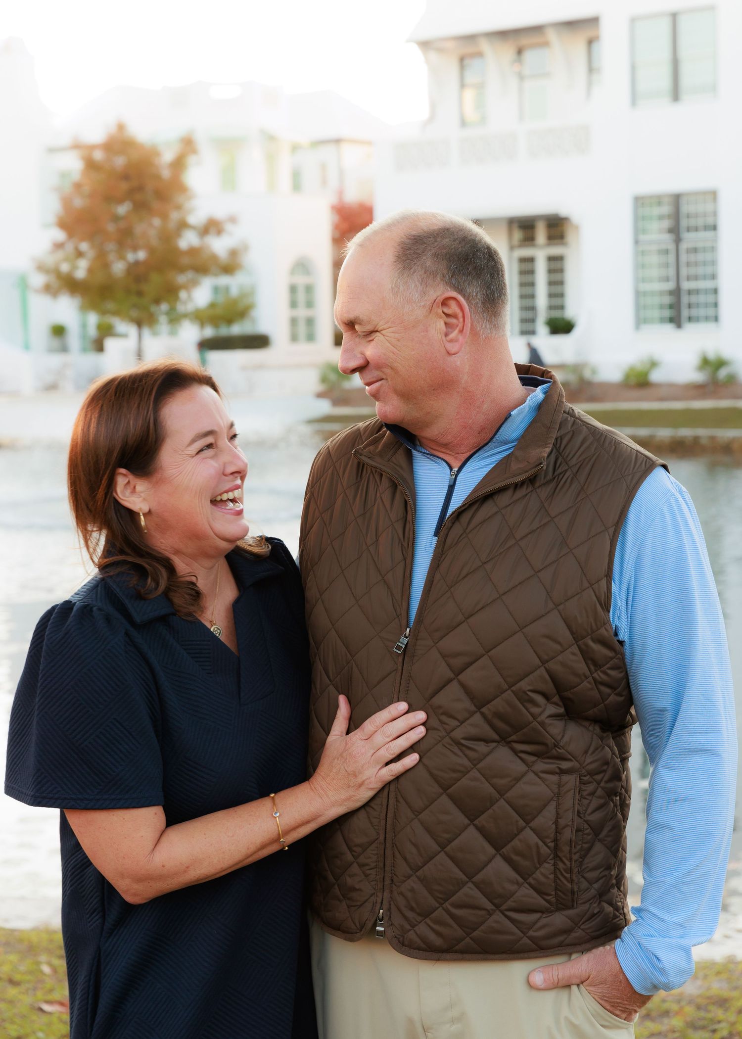 Candid moments of a couple laughing together outdoors by a lake.