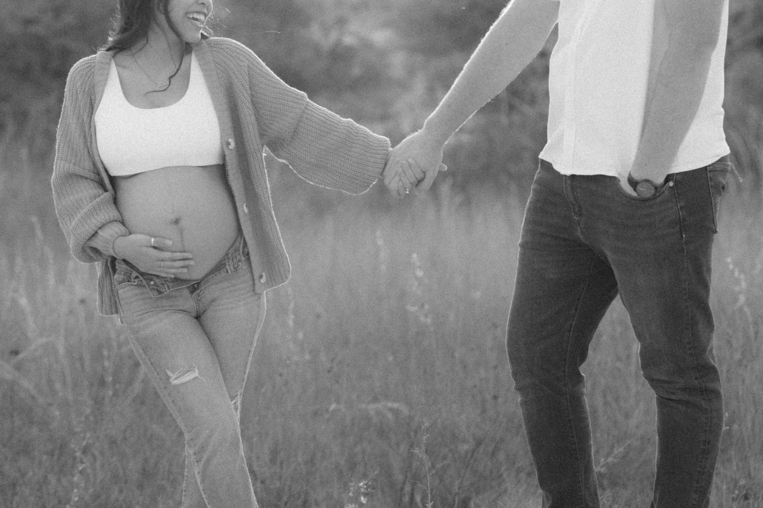 A series of black and white maternity photos showing a pregnant woman in a field at sunset.