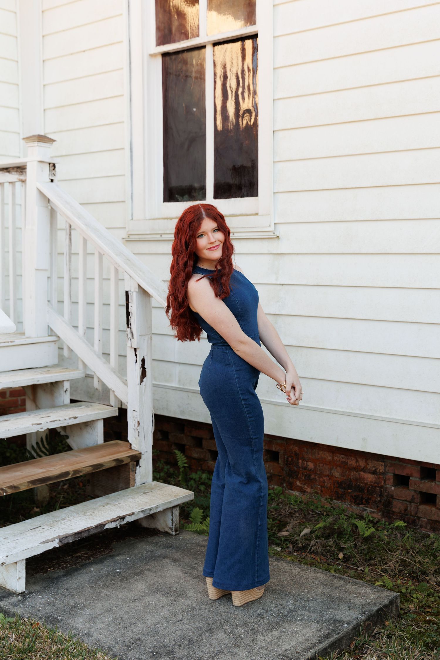 A woman in a navy blue dress poses on white wooden porch steps in a series of four connected photos.
