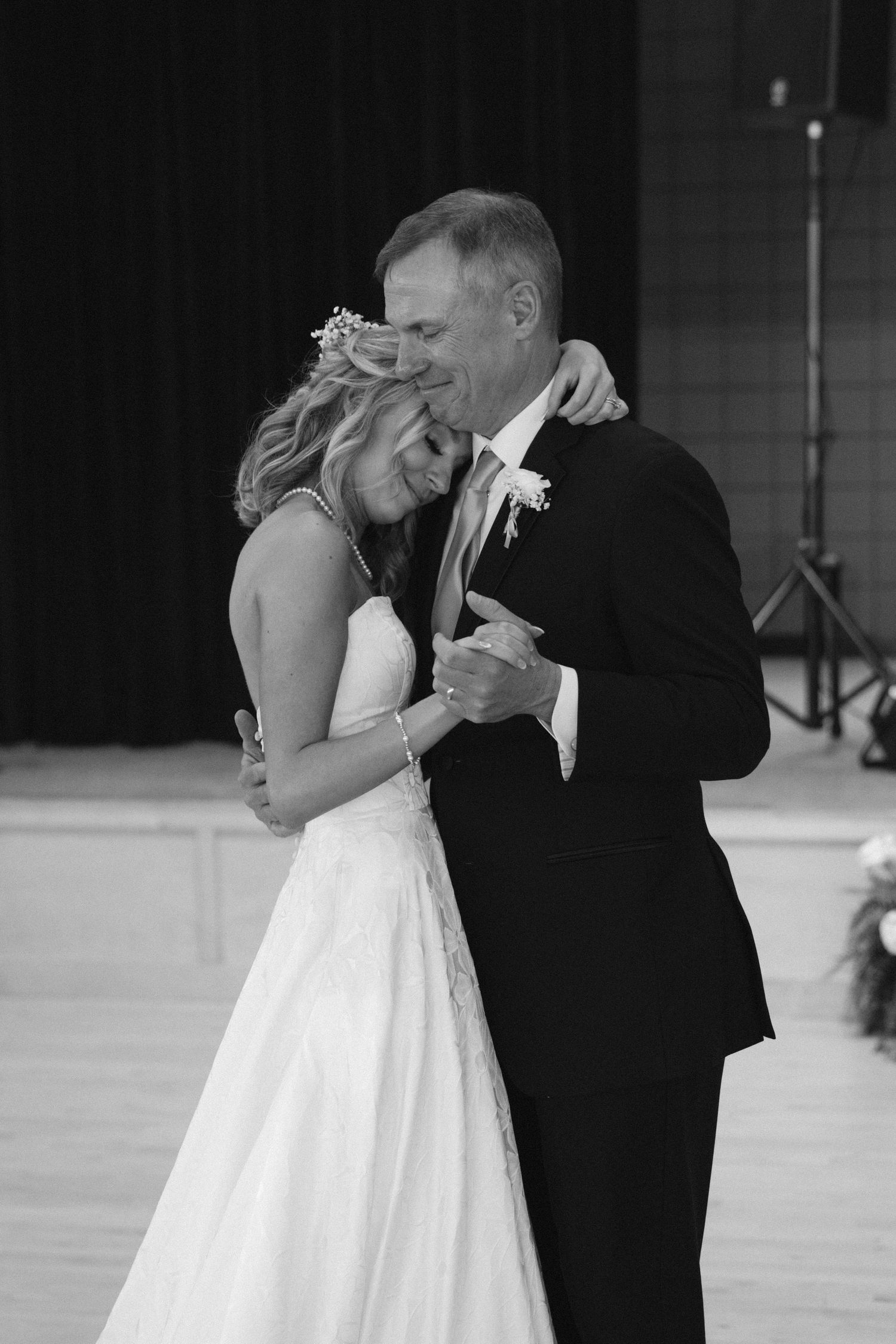Tender black and white moment during wedding dance on hardwood floor.
