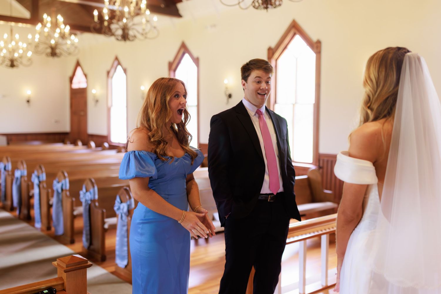 An elegant wedding scene in a historic chapel with blue accents and wooden pews.