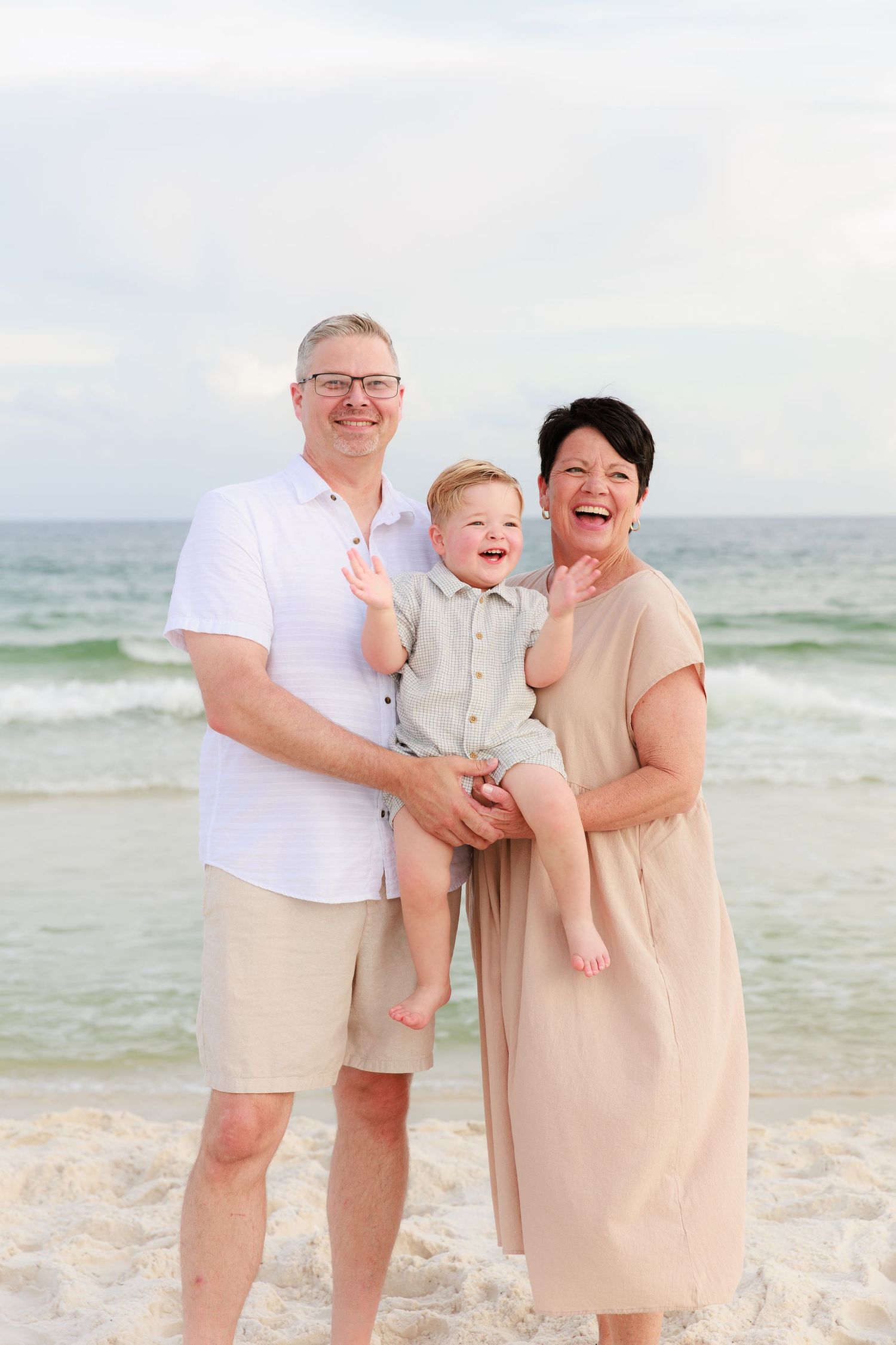 A joyful family moment captured on a sunny beach with waves and sand in the background.