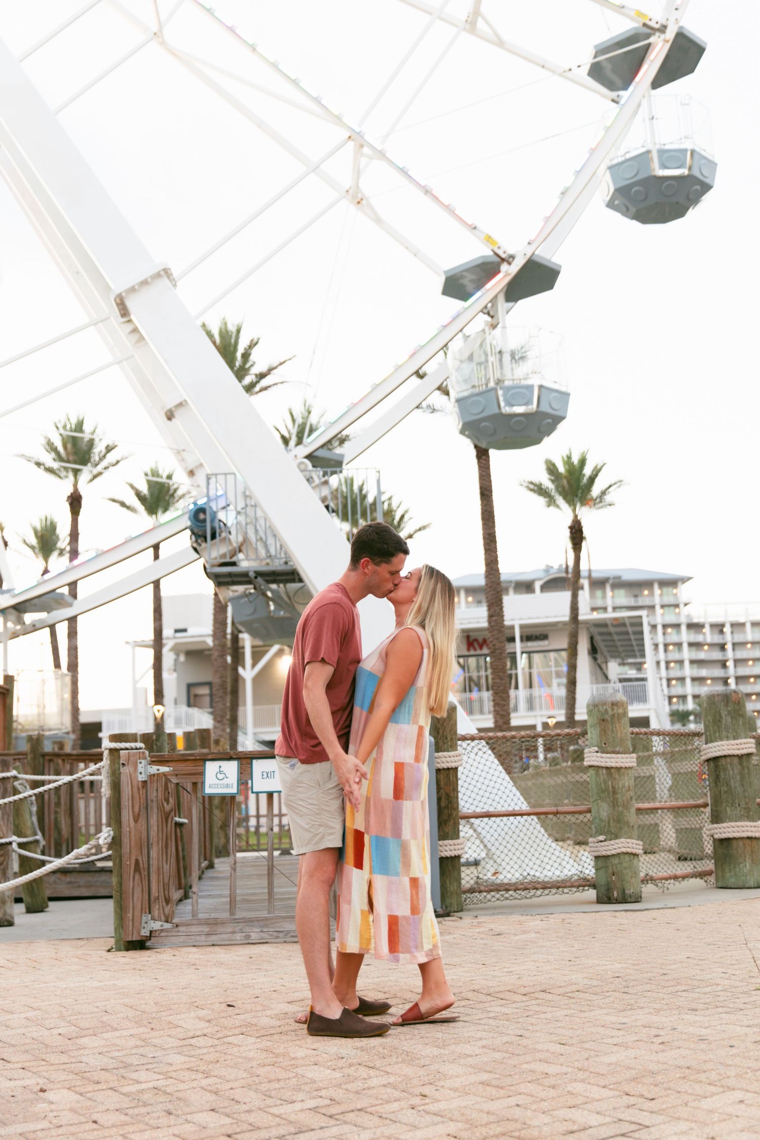 Couples share intimate moments under a white canopy structure with palm trees in the background.
