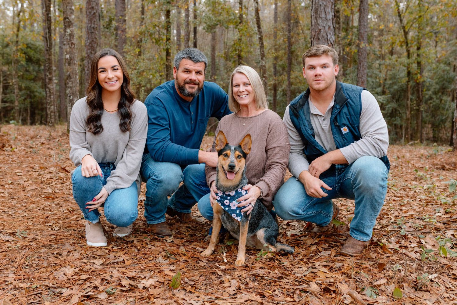 Group photo of people sitting on fallen autumn leaves in wooded area.