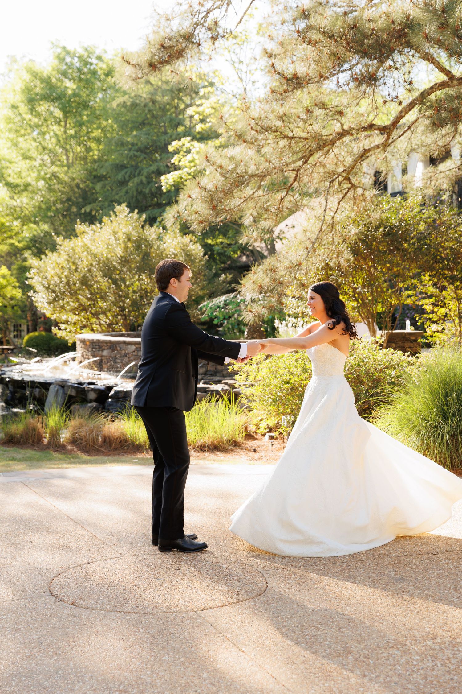 Bride and groom dancing outdoors in a lush garden setting, with the bride's white gown flowing gracefully.