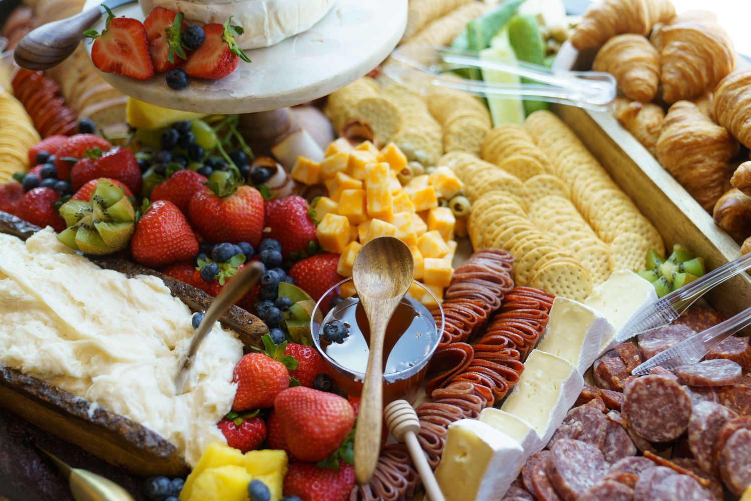 Colorful charcuterie board with assorted meats, cheeses, fruits and snacks arranged for entertaining.