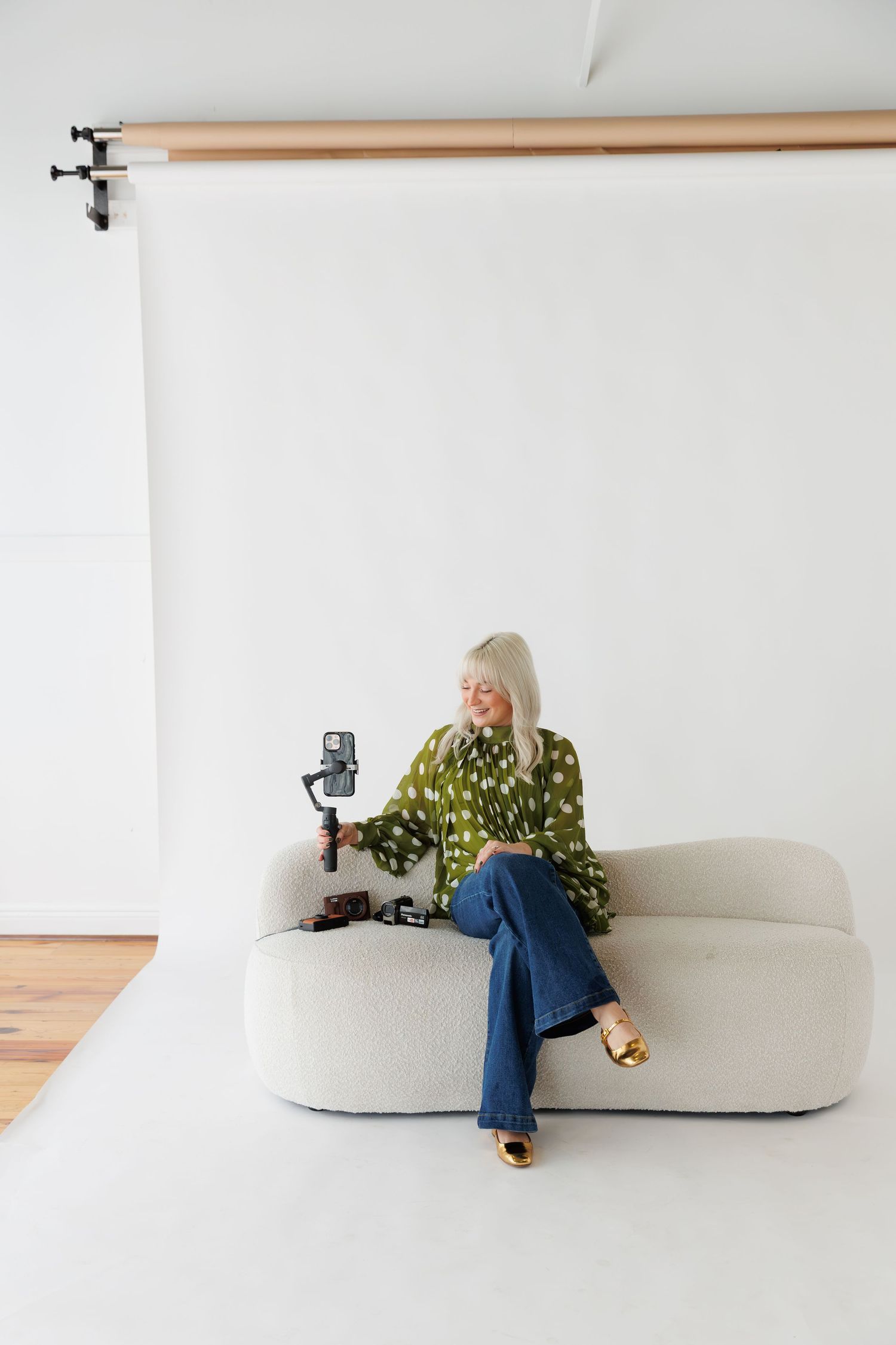 A minimalist white studio setup with a curved bench and camera equipment for professional photography.