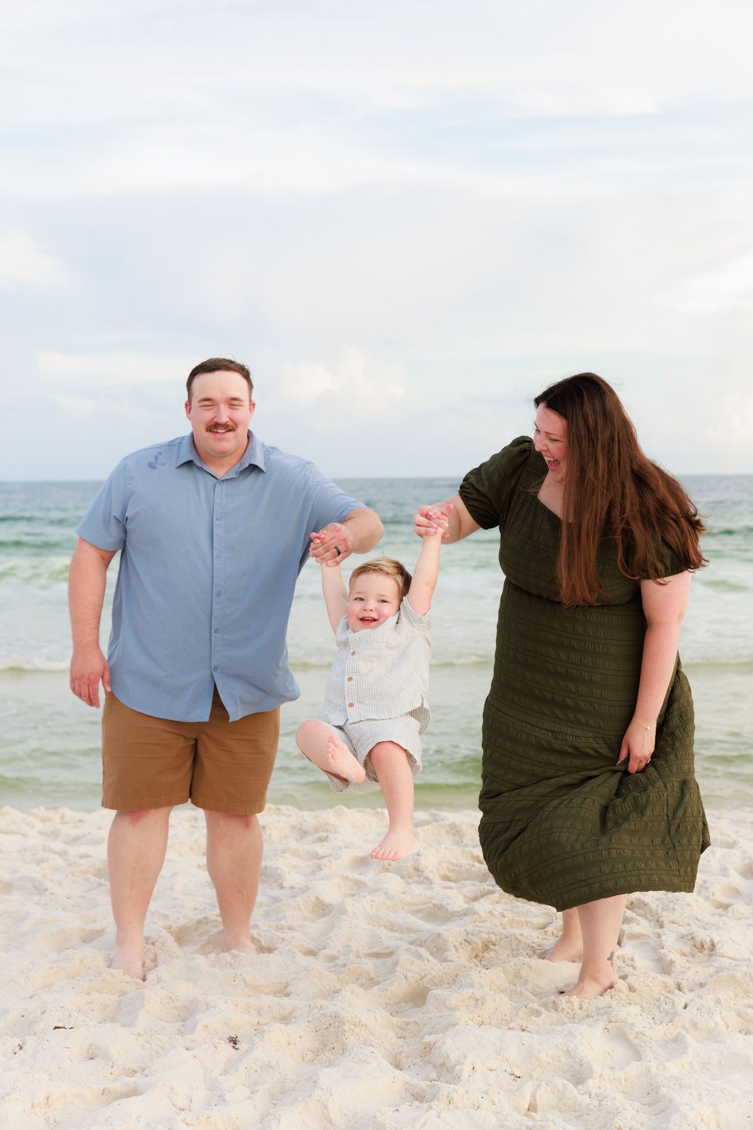 A playful family moment captured in a series of photos on a white sandy beach with gentle waves behind them.