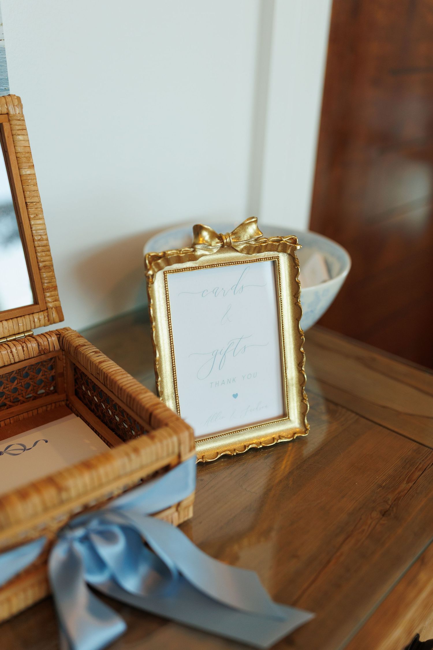 Table display of wooden and gold ornate vintage picture frames with soft blue decor accents atop wooden surface.