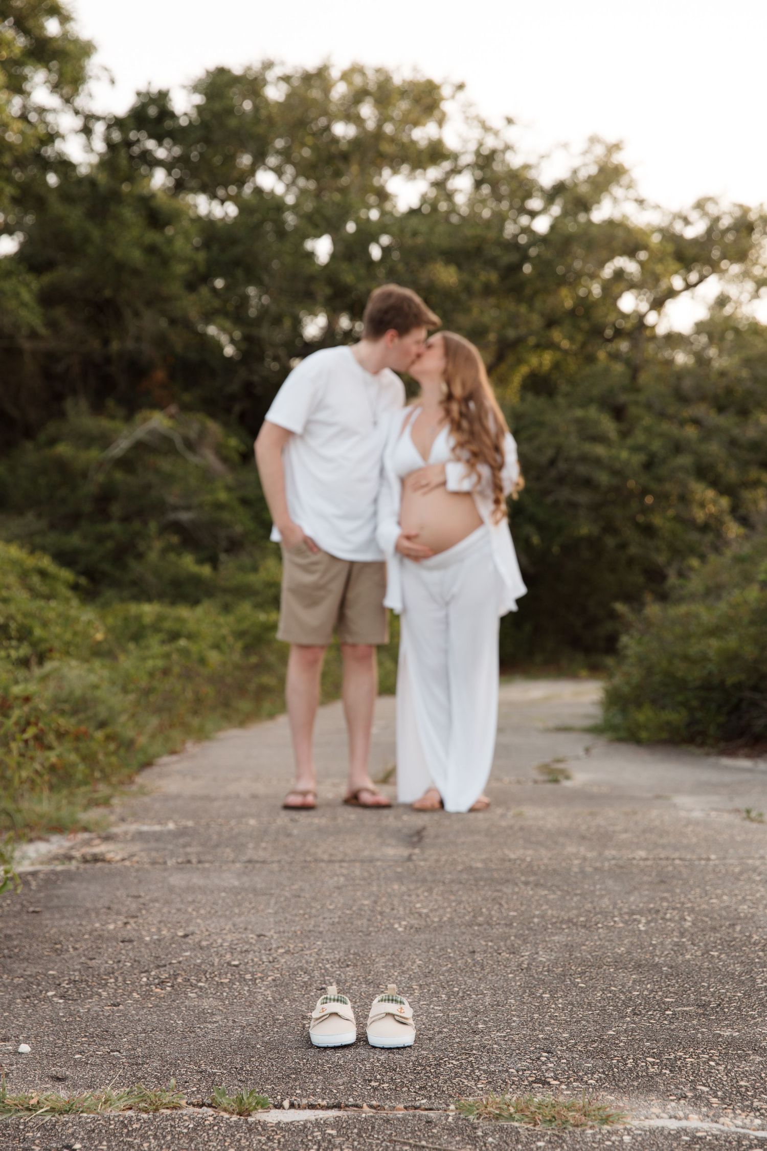 Artistic shoe-level photo of couple standing together on concrete path with greenery in background.