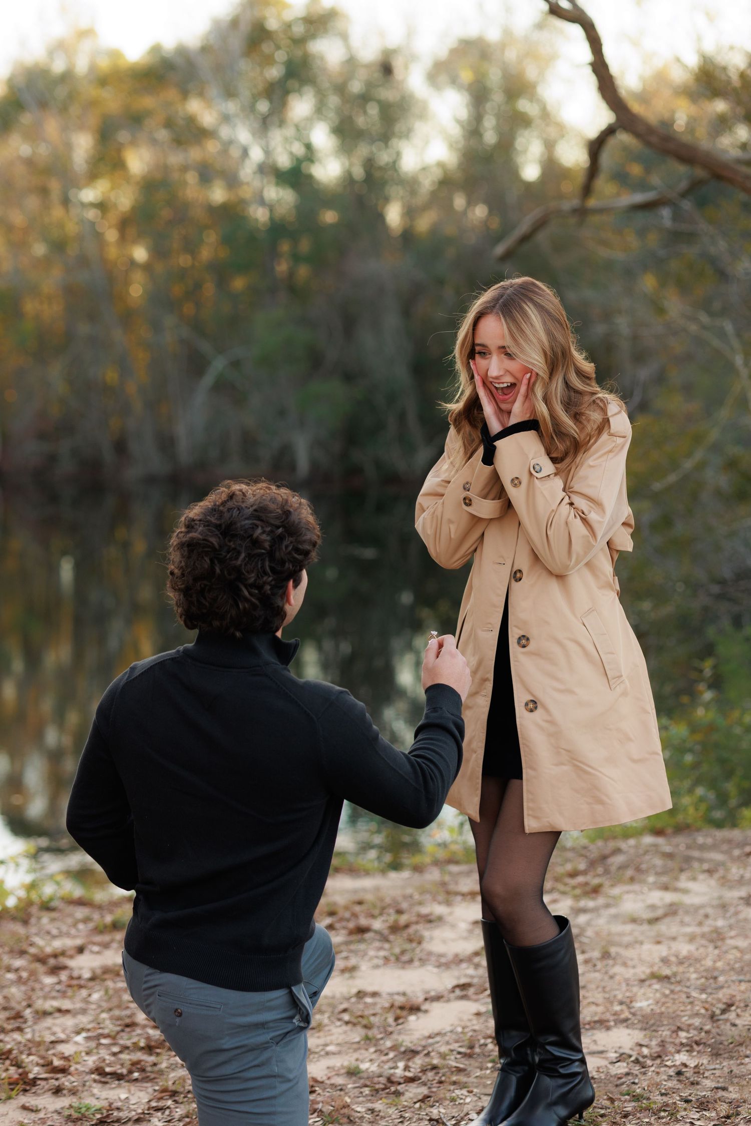 A couple shares a candid moment during an outdoor photoshoot in a wooded area during autumn.
