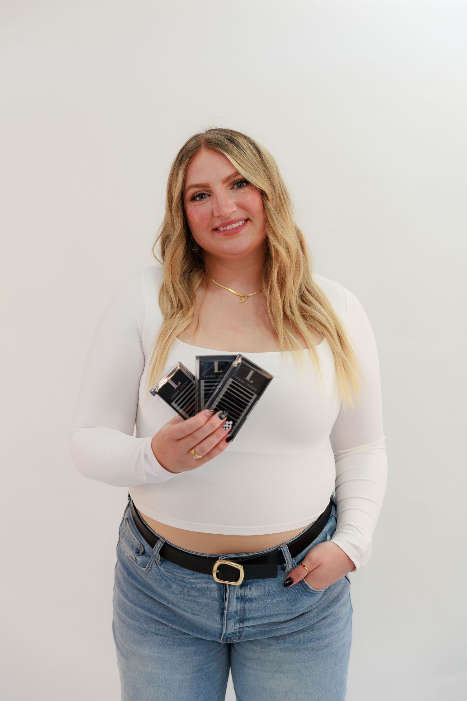 Professional holding business cards while wearing white top and jeans.