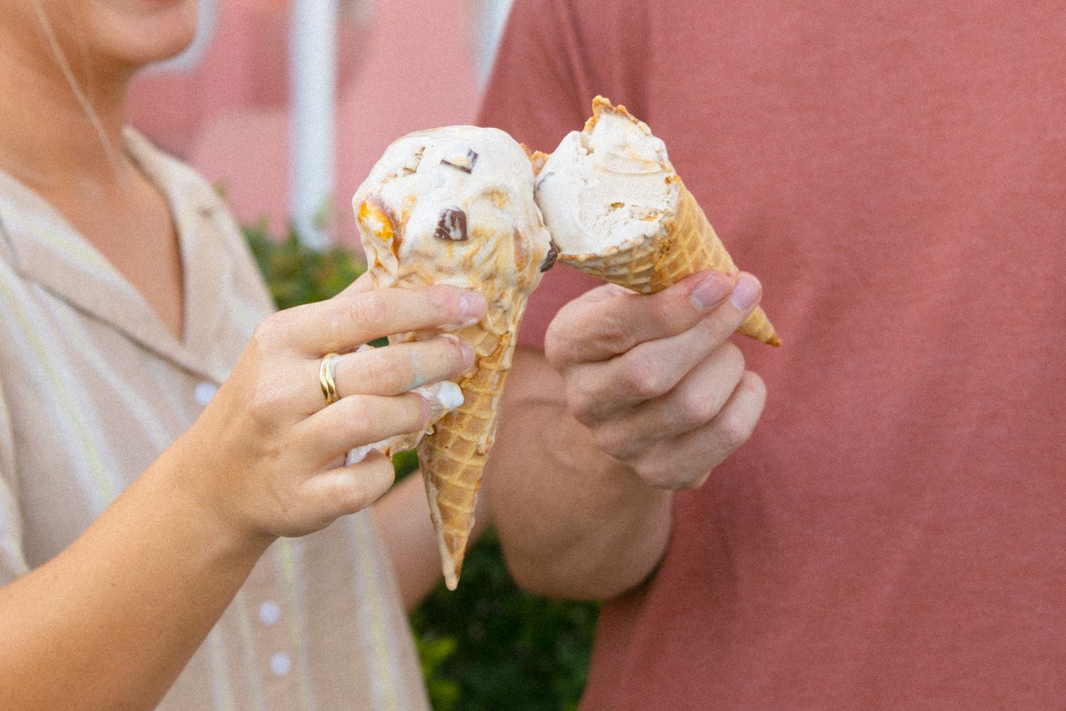 Close-up of hands holding waffle cones filled with scoops of ice cream.