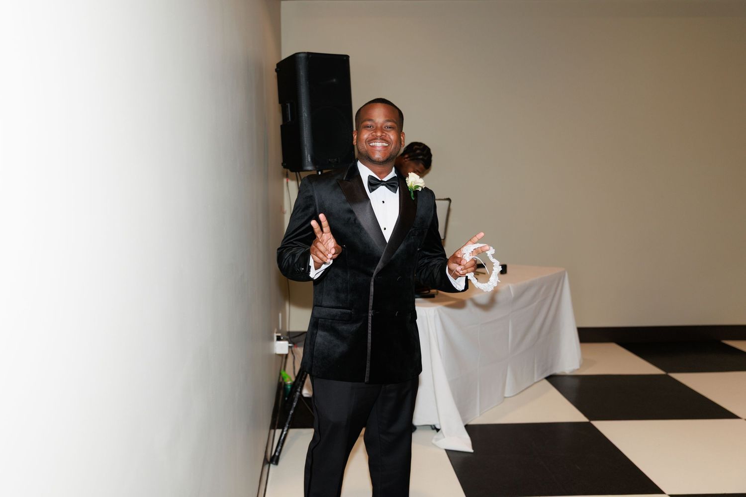 Guests dance and celebrate on a black and white checkered floor at a wedding reception.