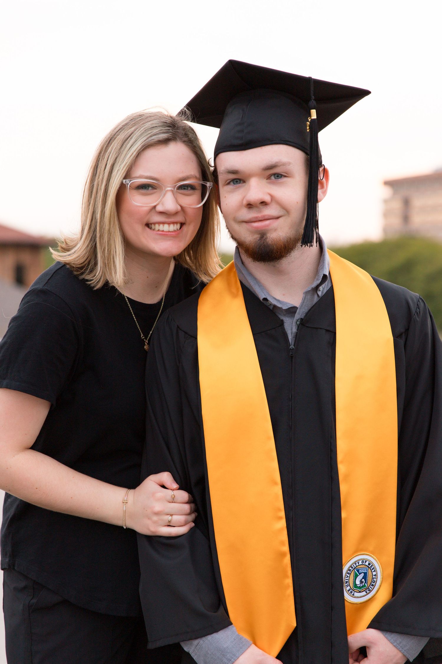 Graduation ceremony portrait with yellow honors stole and black cap and gown.