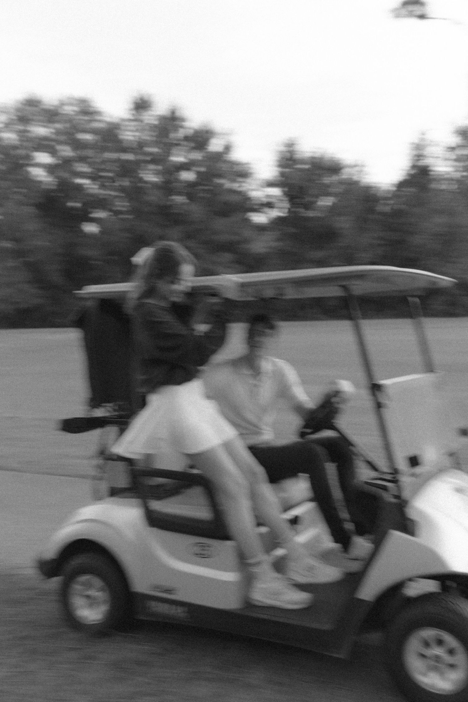 Blurred motion shots of people riding in a golf cart across the course.