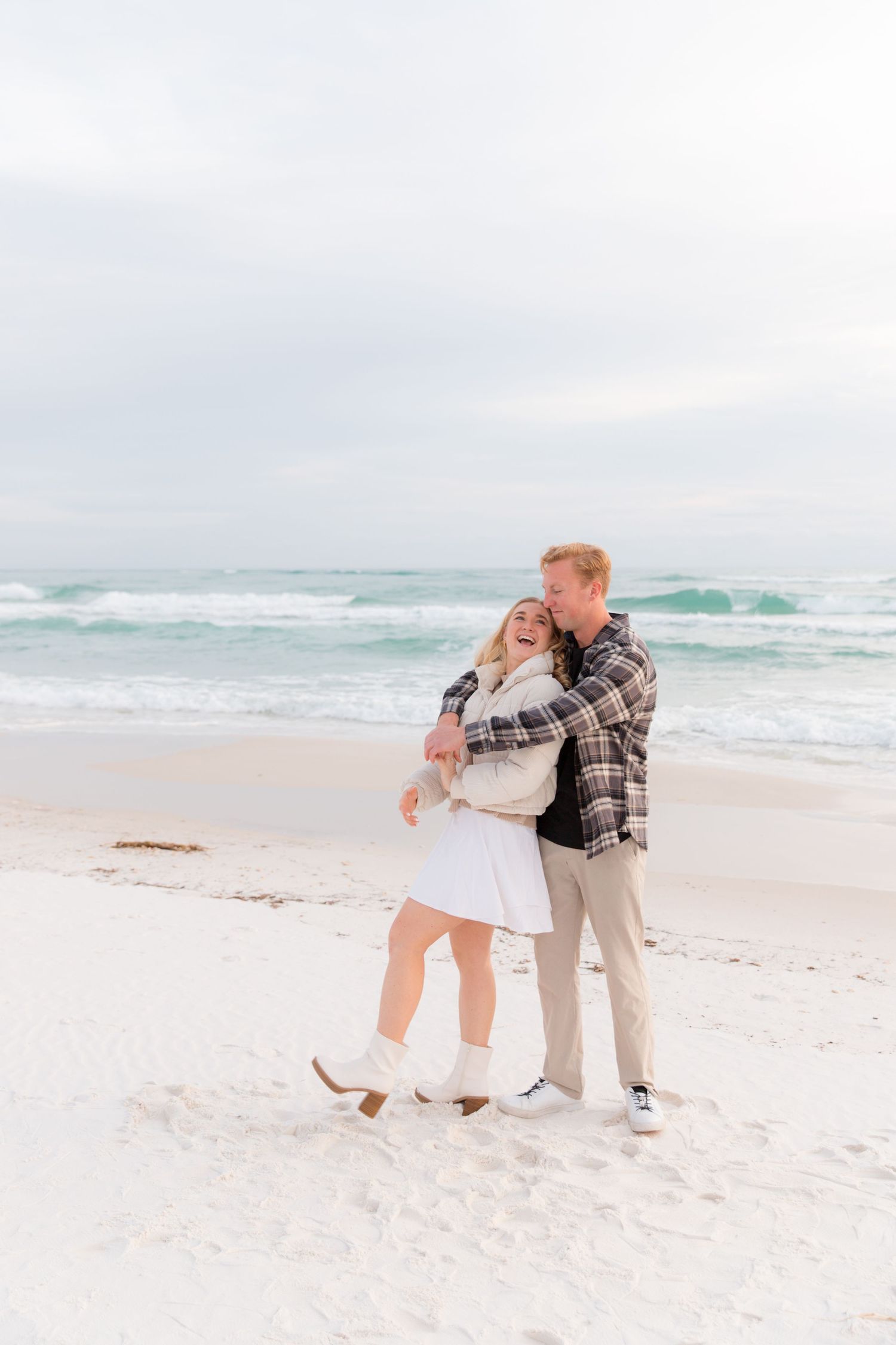 A sweet proposal moment captured on a sunny beach with waves crashing in the background.