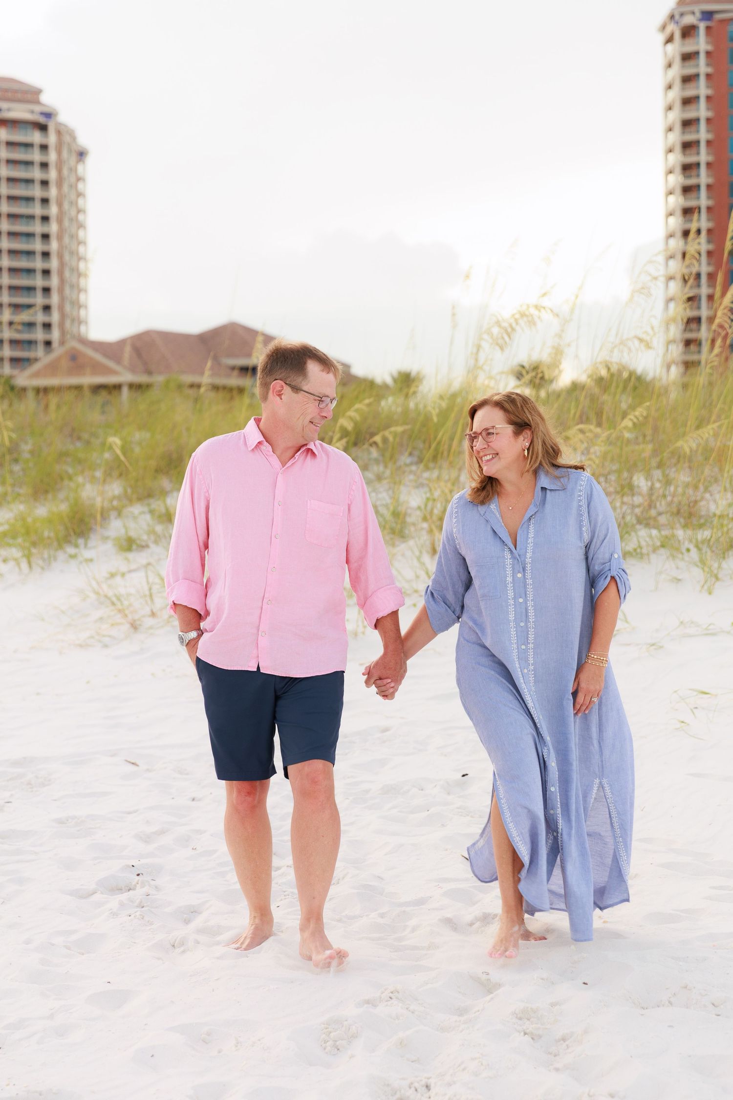 Playful interaction between two people walking along a pristine beach near coastal condominiums.