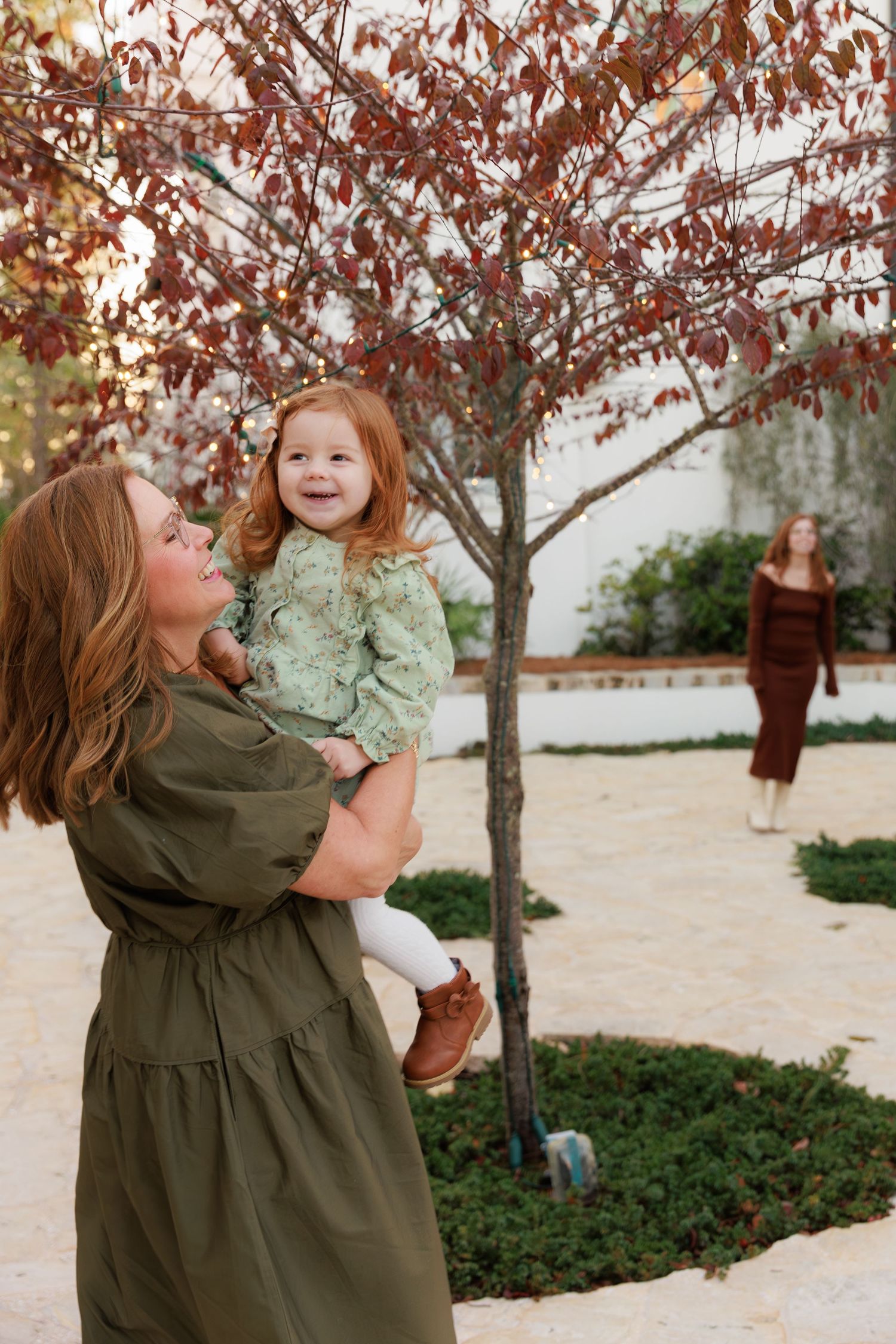 Mother and daughter share joyful moments together under autumn trees in a garden setting.