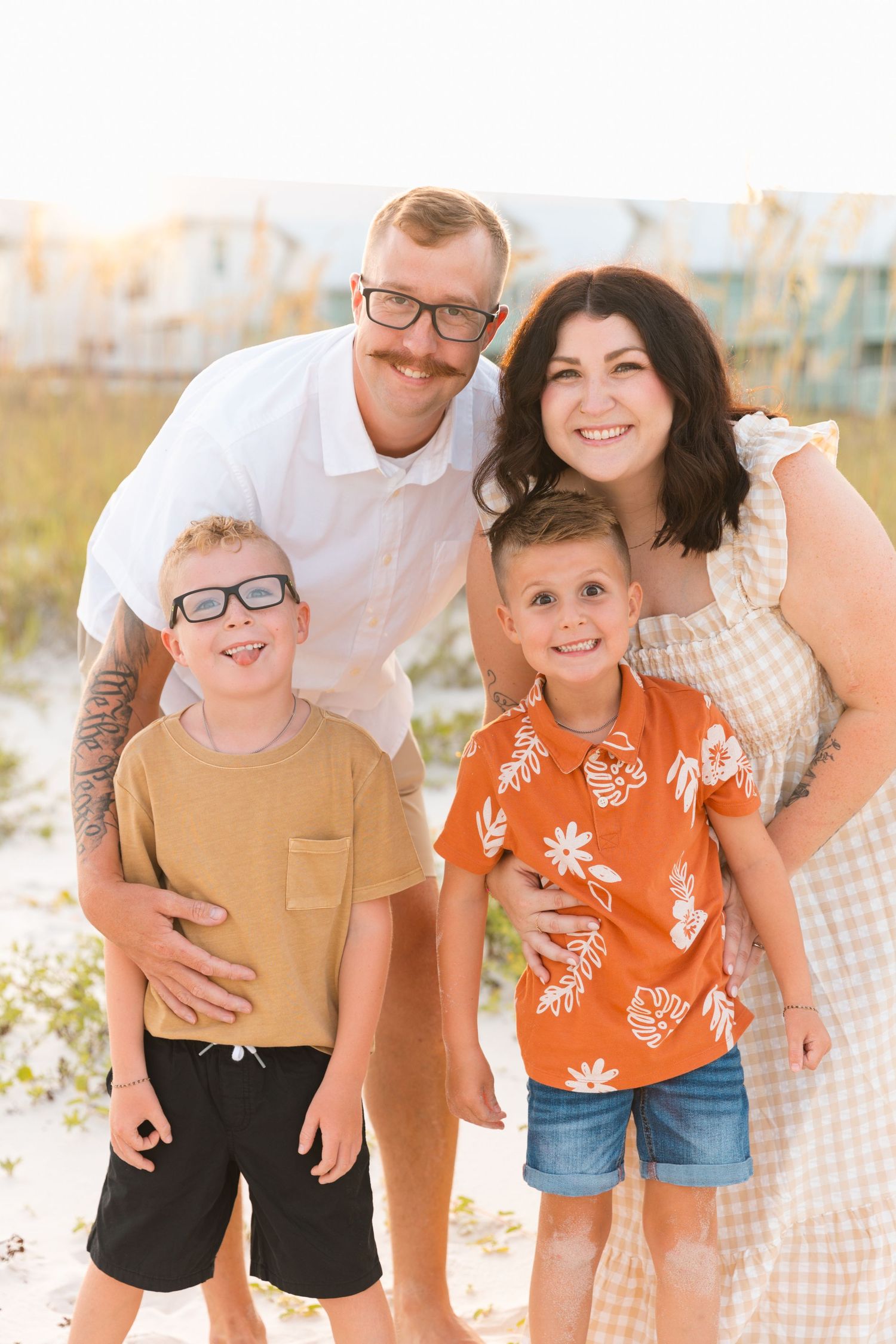 A cheerful family of four poses together outdoors in summer clothing.