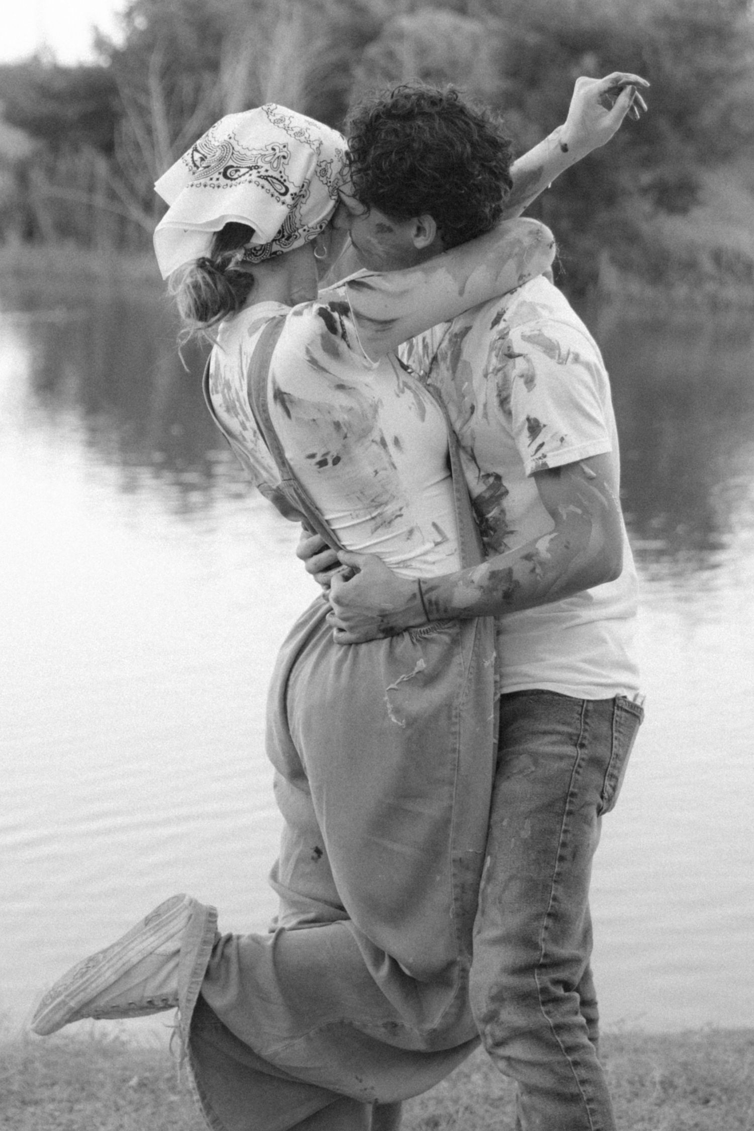 A romantic couple shares tender moments by a lake in a series of black and white photographs.
