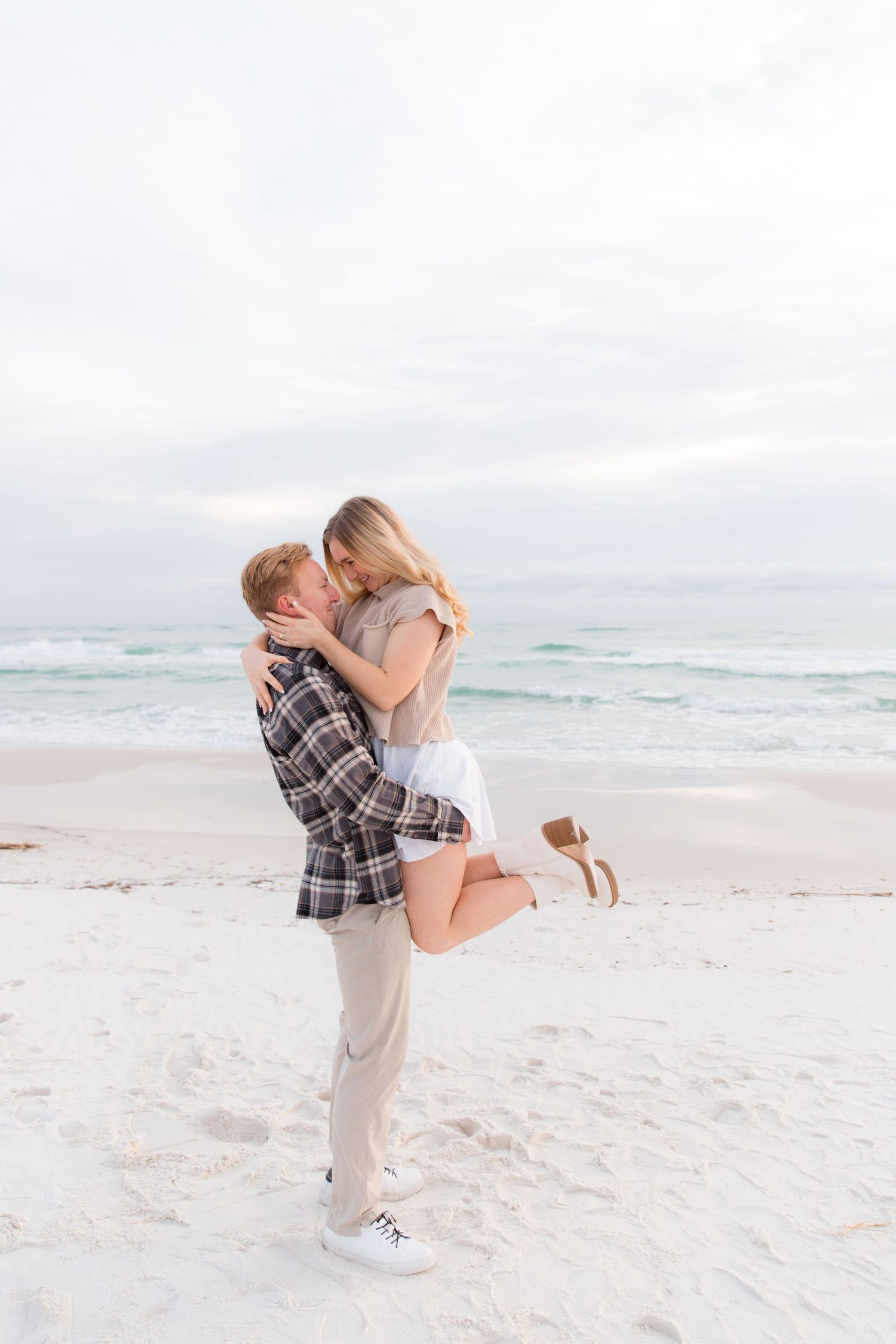 A romantic beach photoshoot sequence showing a couple embracing on white sand with ocean waves in the background.