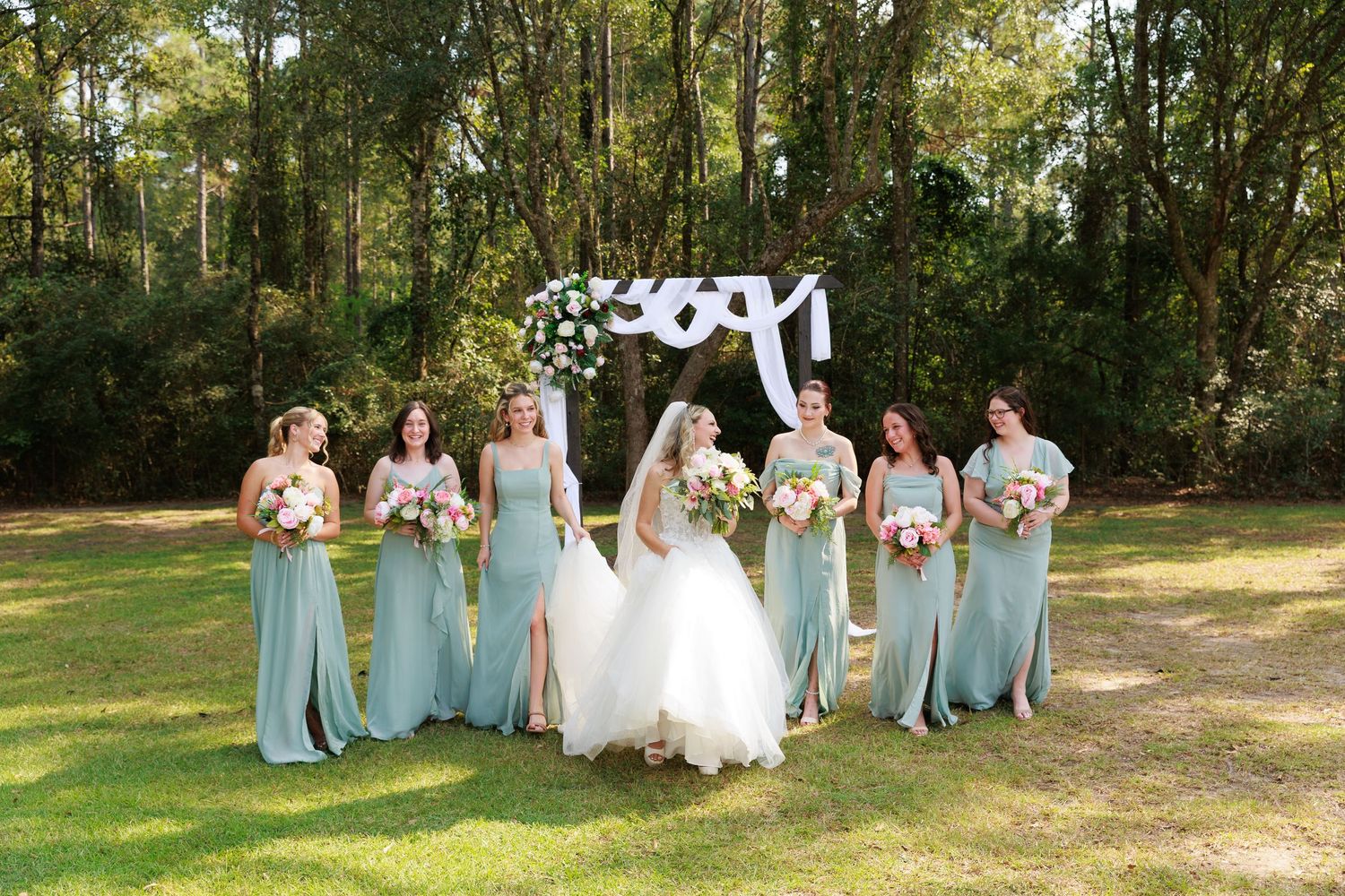Wedding party poses in front of 2021 balloon sign with bridesmaids in mint dresses and bride in white gown.