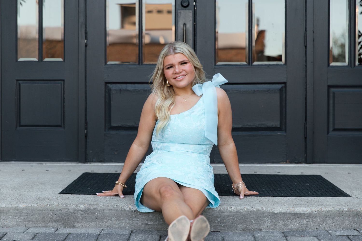 A person in a light blue outfit poses on steps in front of black doors in multiple similar shots.