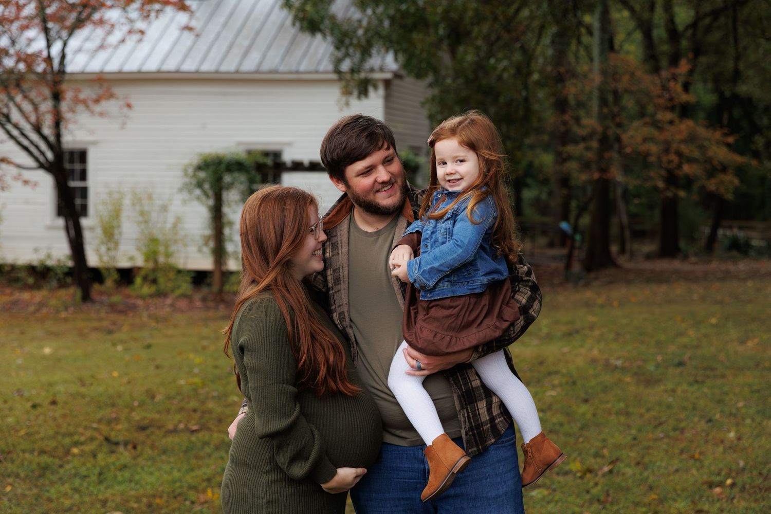 A couple shares tender moments outdoors during a fall photoshoot in a wooded setting.