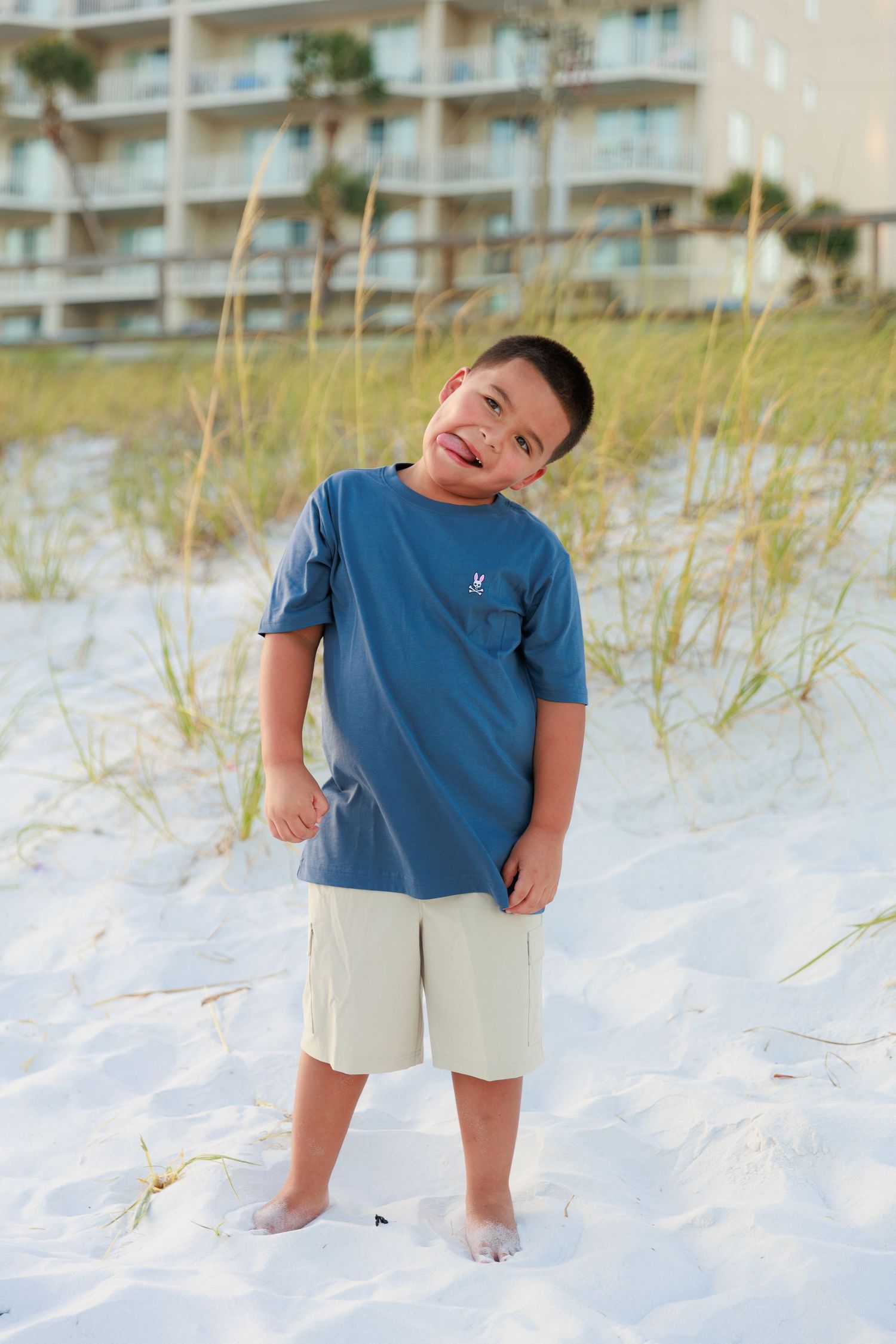 A series of playful poses on a white sandy beach with beach condos in the background.