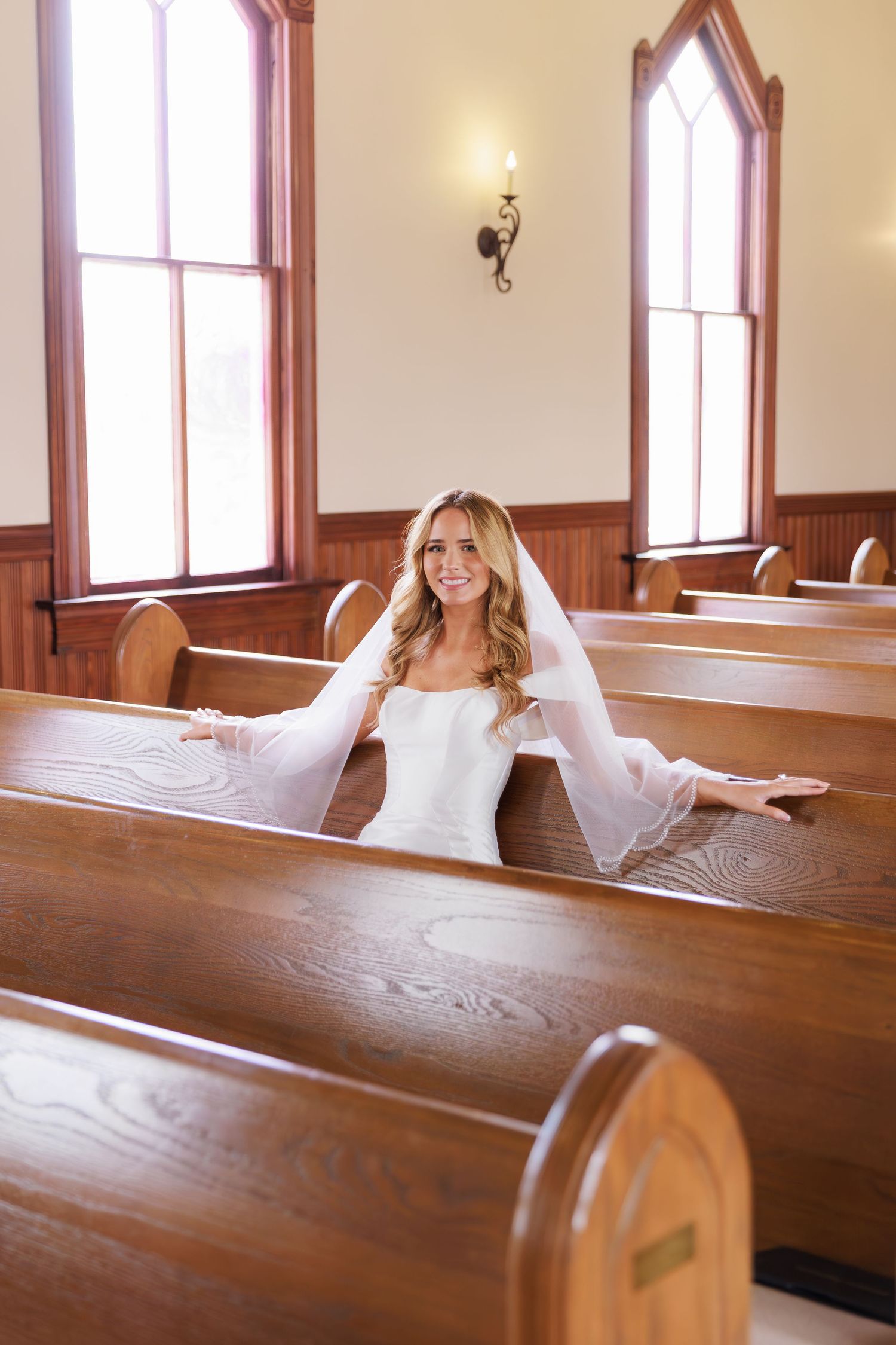 A bride in a white wedding dress lounges playfully across wooden church pews in a series of connected photos.
