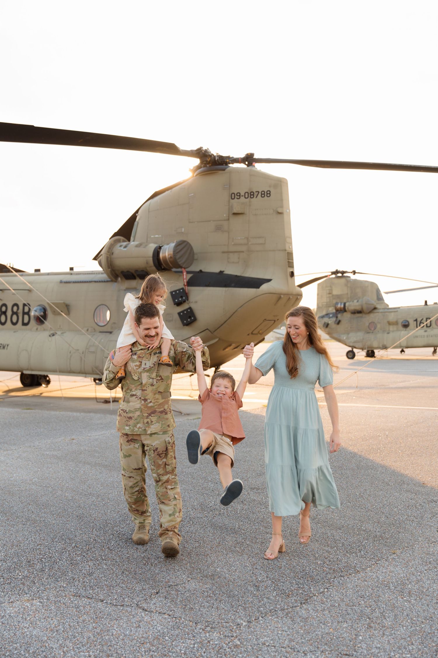 Group walking together on tarmac with large military helicopter in background.