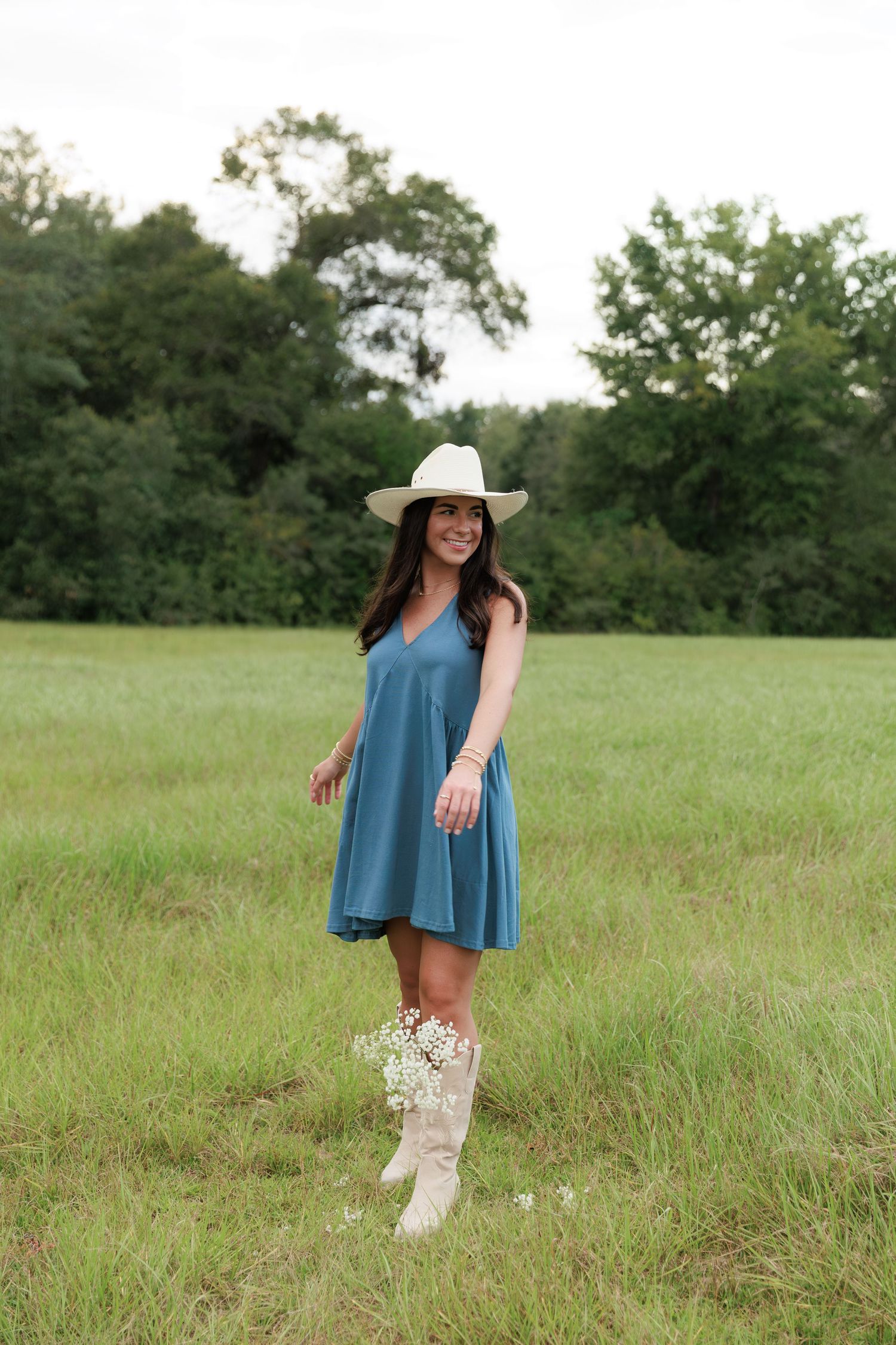 Cowgirl chic outfit with a blue swing dress and embellished boots in a sunny meadow.
