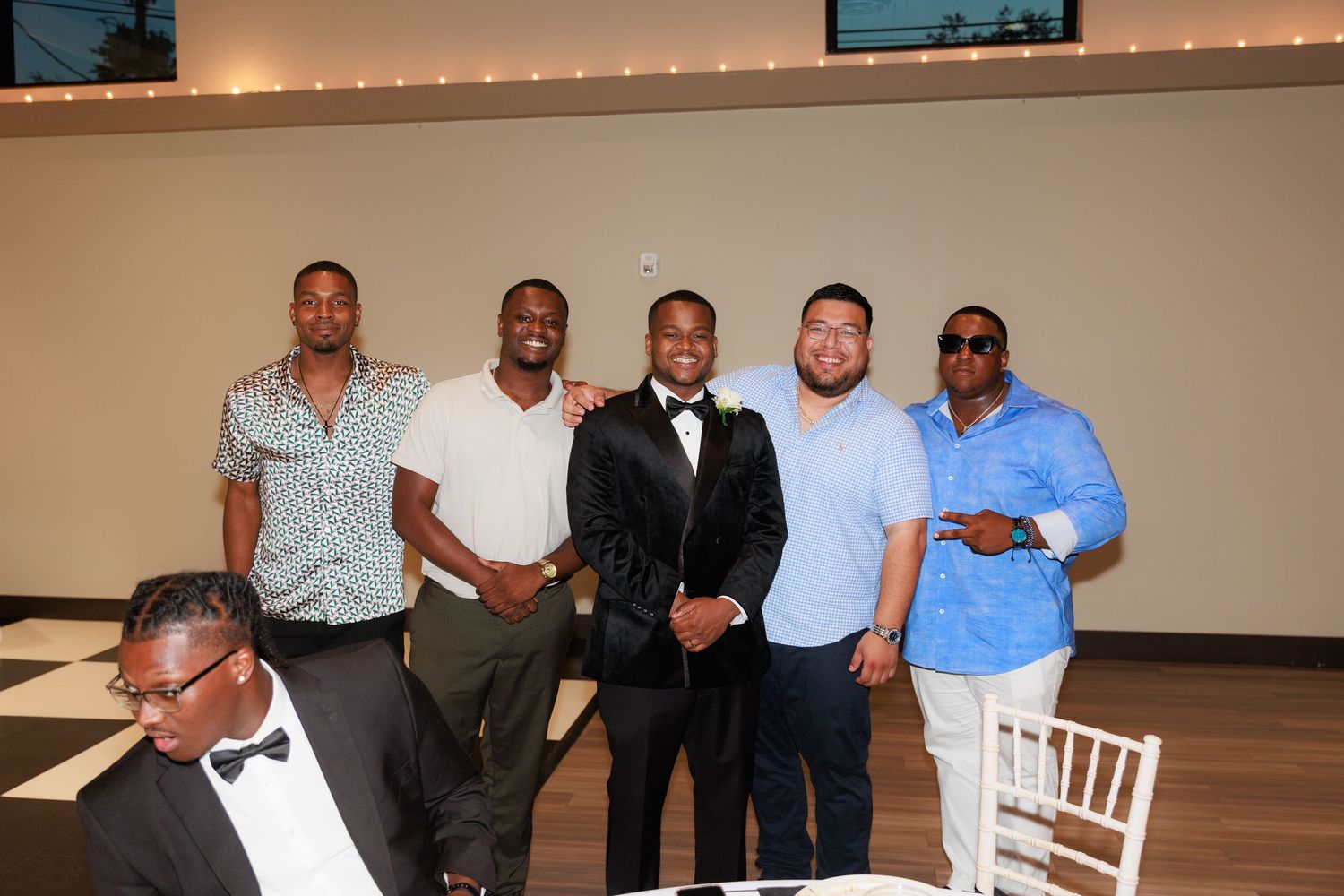 A group of guests in formal attire gather and socialize during a wedding reception.
