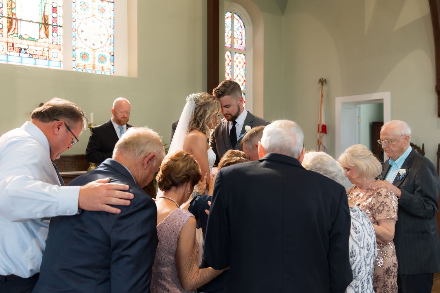 Wedding attendees and party members gather in church pews during ceremony.