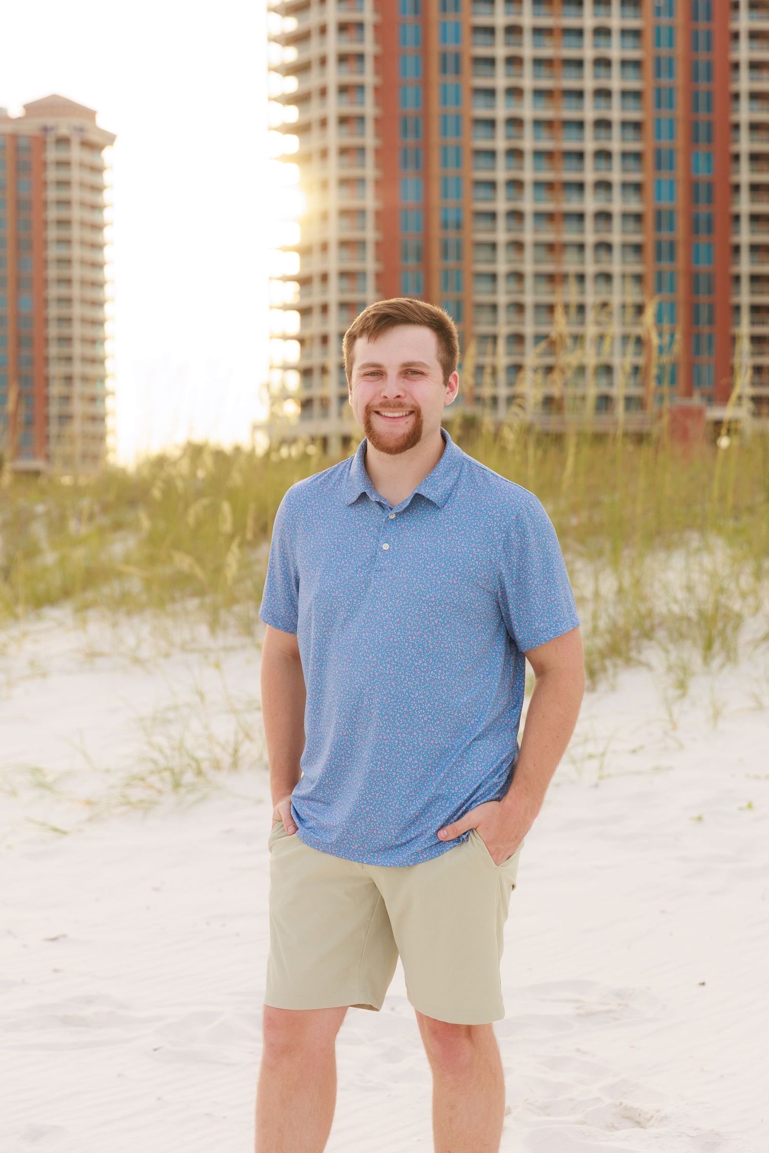 A series of photos showing someone in a blue polo shirt and khaki shorts posing on a white sandy beach with condos in background.