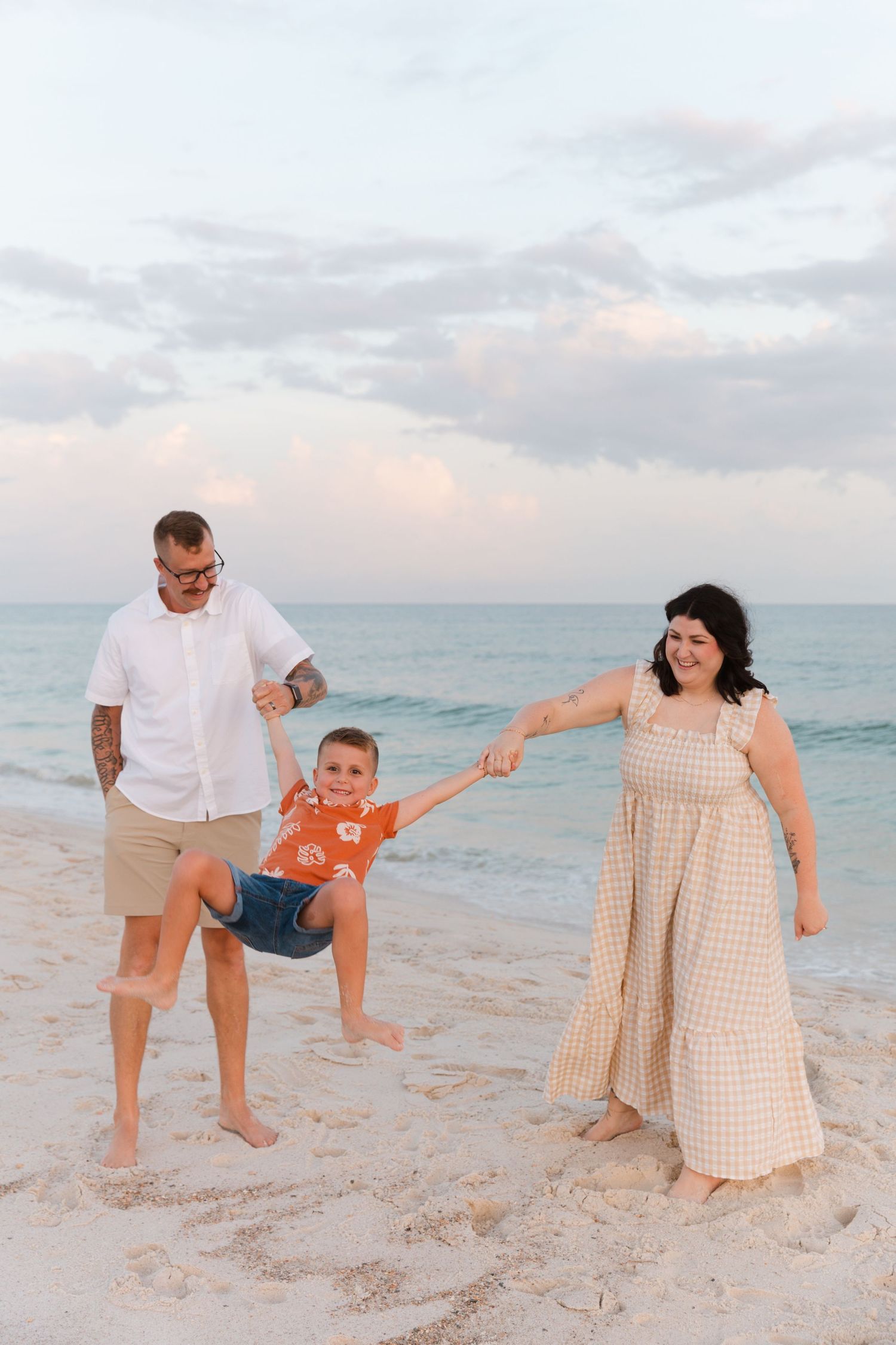 Playful beach family photo sequence showing parents swinging child in the air at sunset.