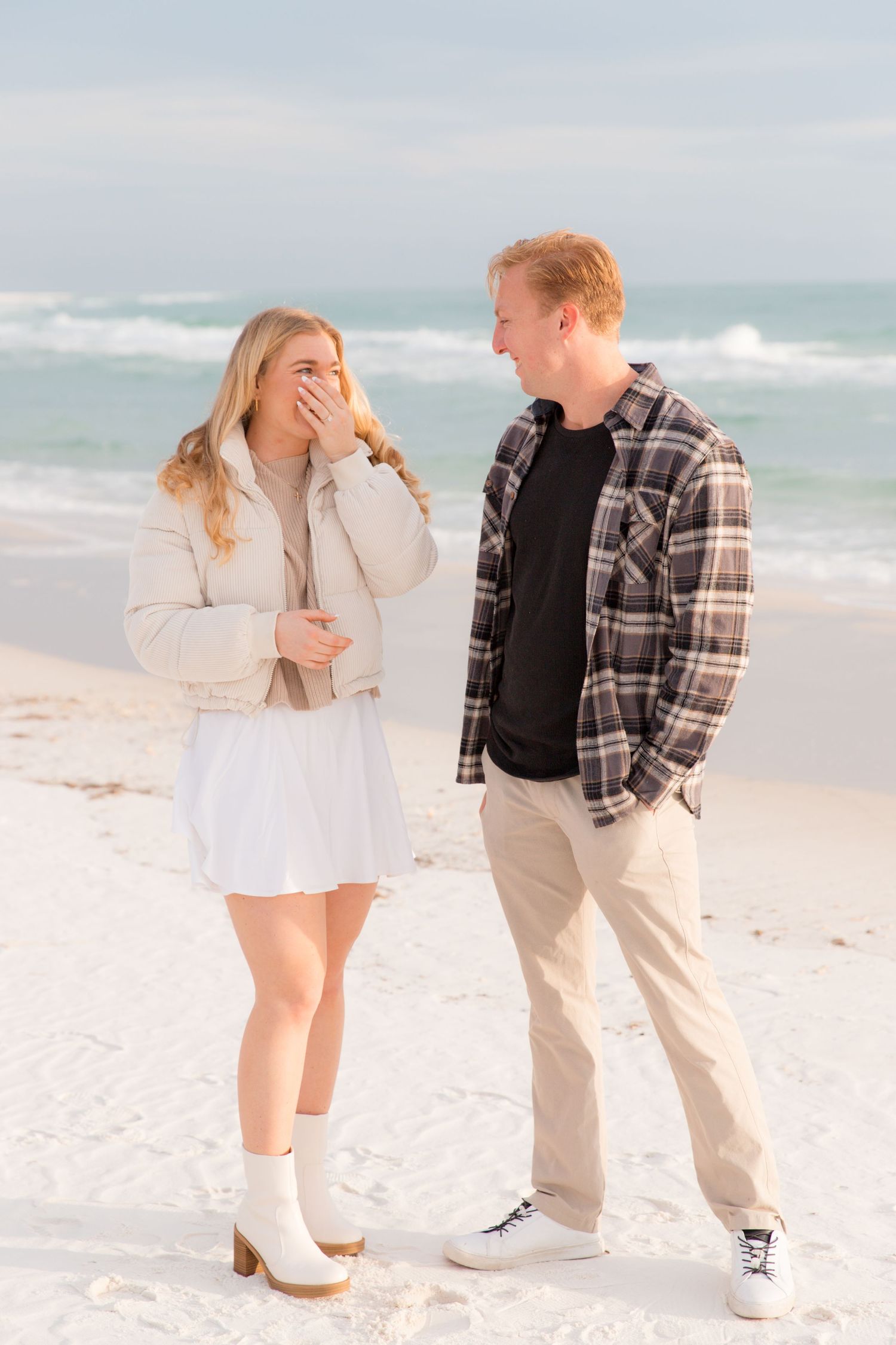 A couple shares a lighthearted moment while walking along the shoreline.