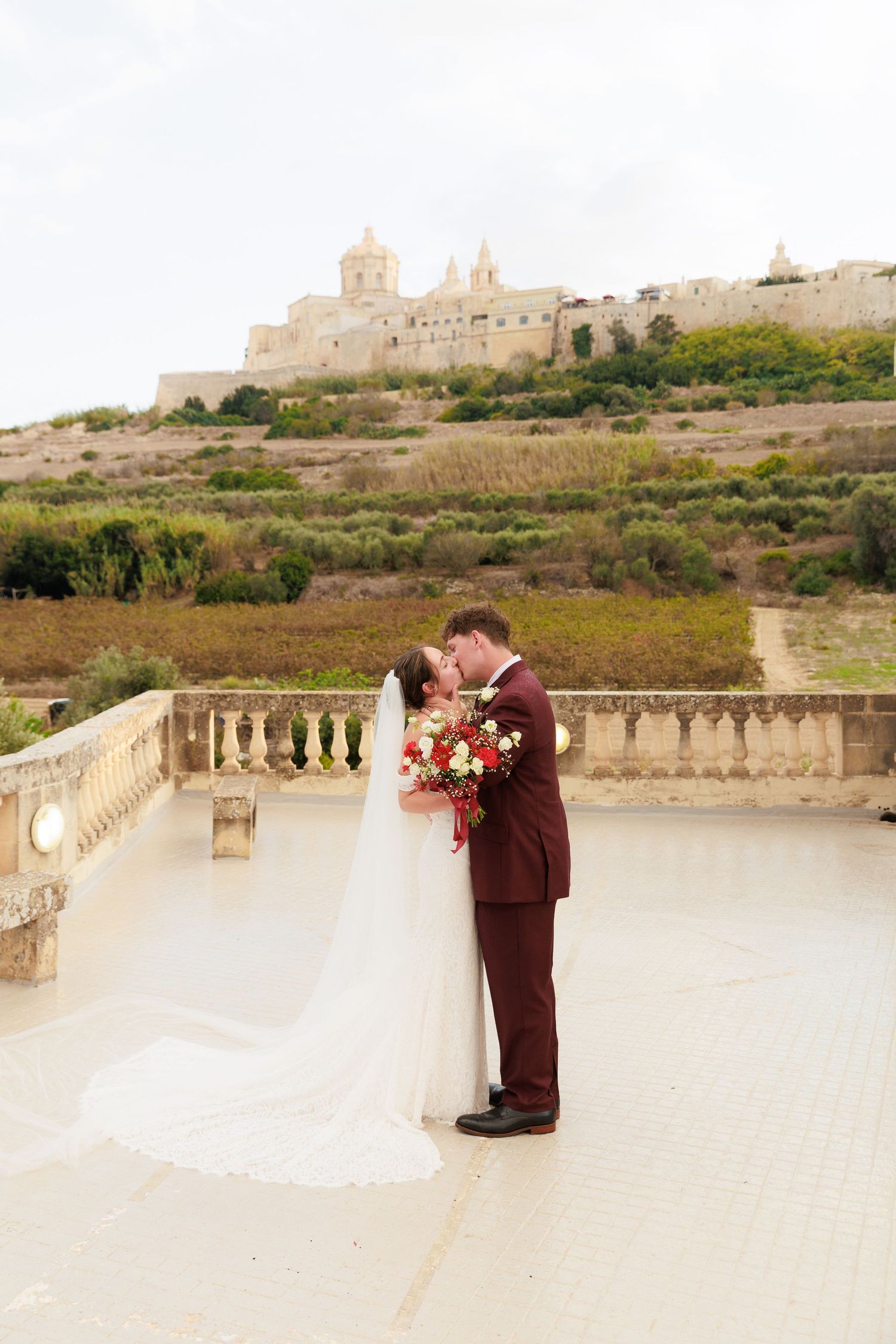 A romantic wedding photoshoot on a stone terrace overlooking historic Mediterranean architecture in Malta.