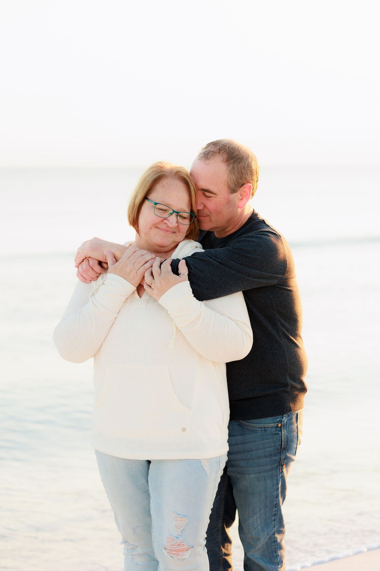 Intimate beach portraits of couple in casual wear against bright white background.