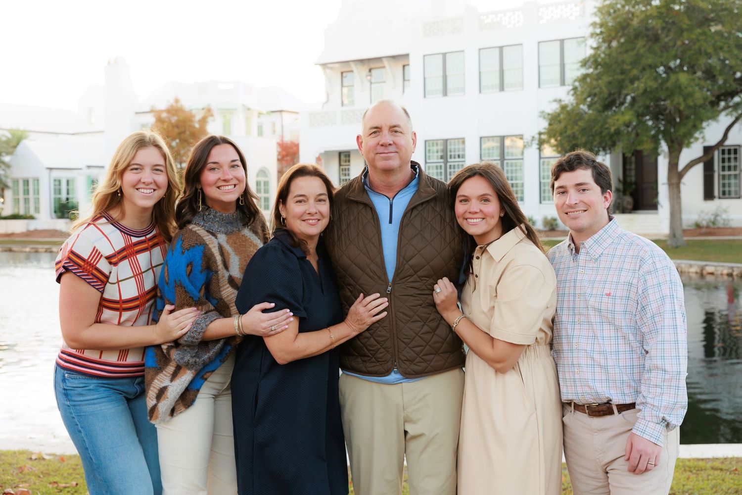 Multi-generational family group poses together outdoors in casual attire.