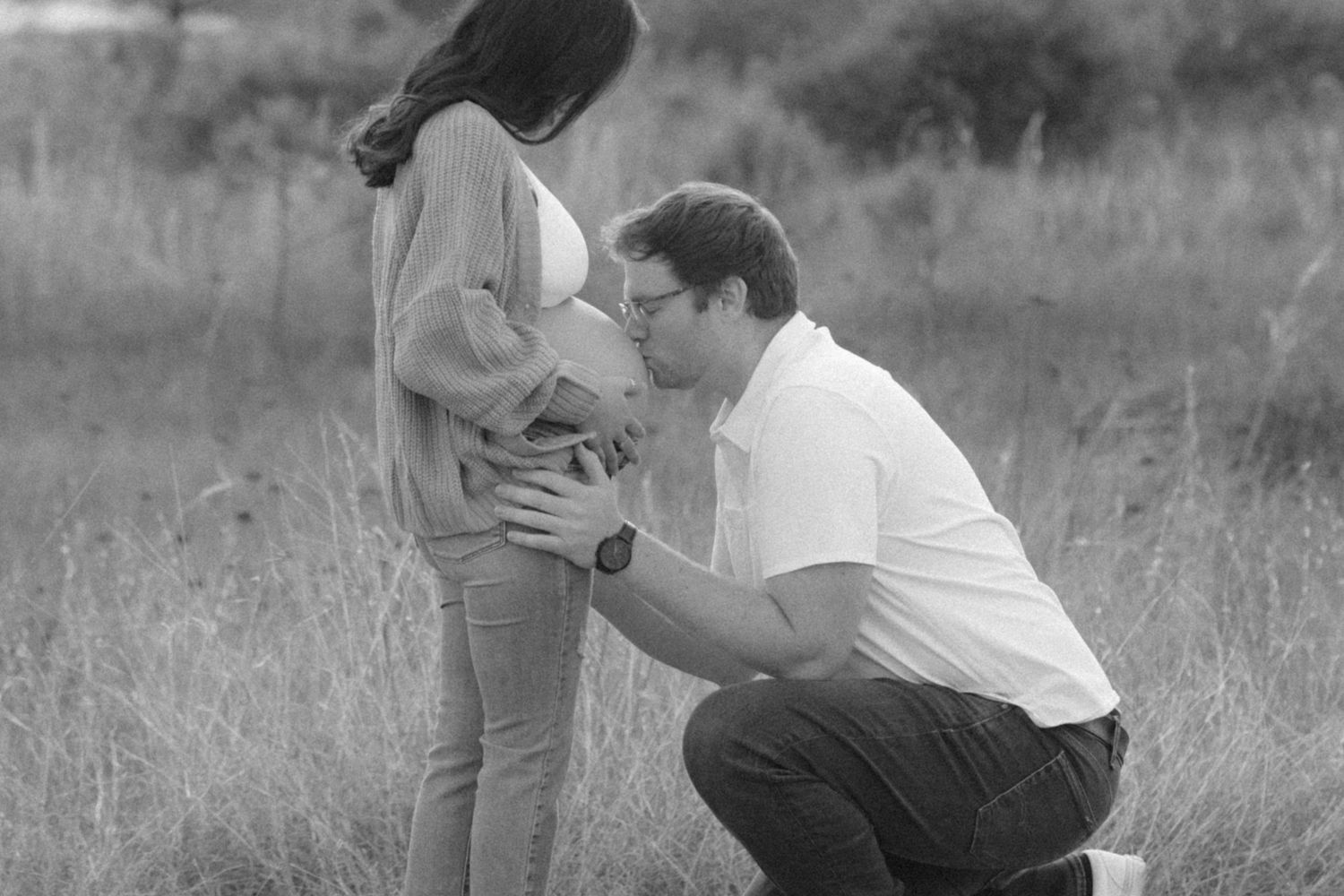 A black and white photo sequence showing a couple playfully interacting and embracing in a grassy outdoor setting.