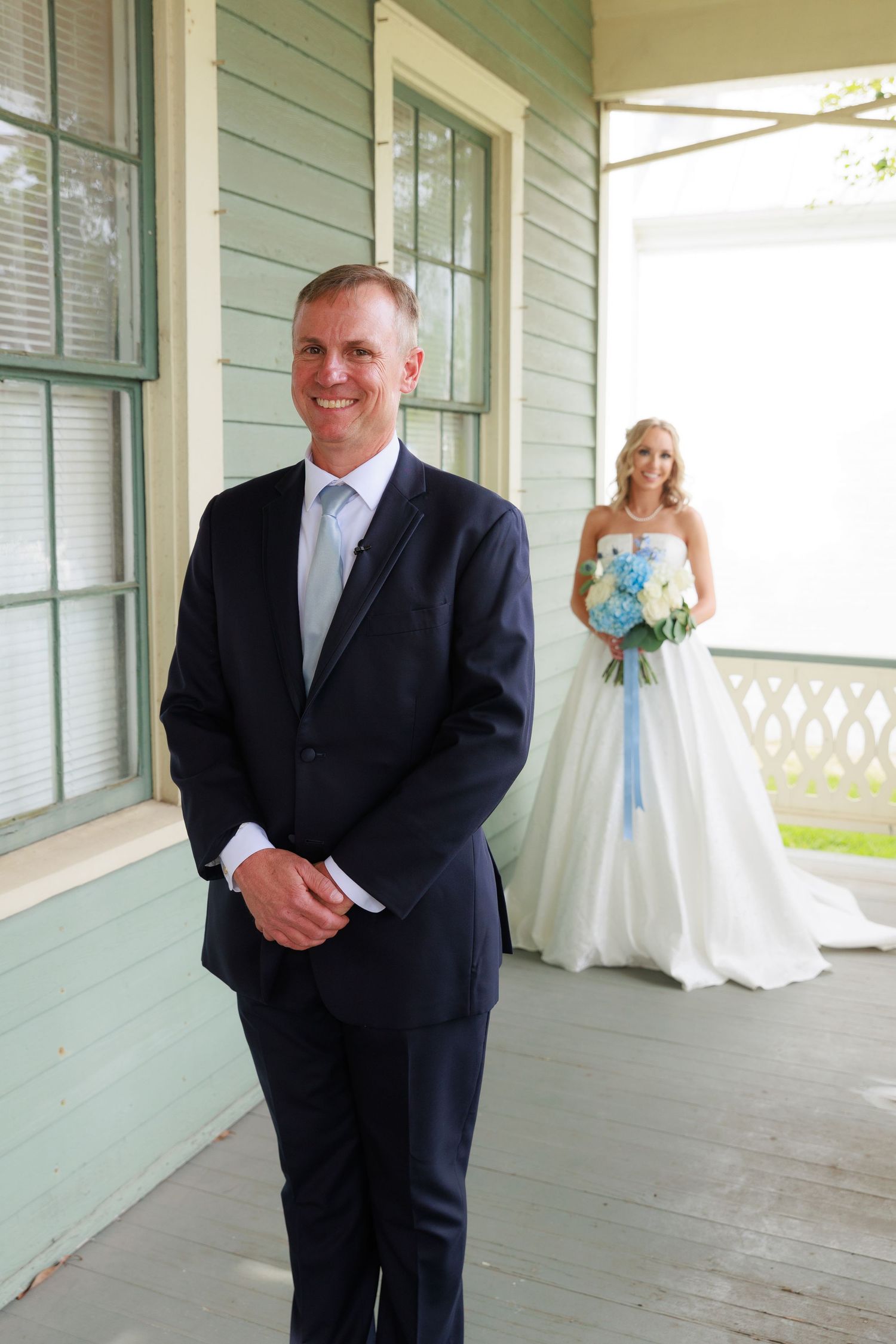 Wedding first look moment on a vintage porch of a mint green house.