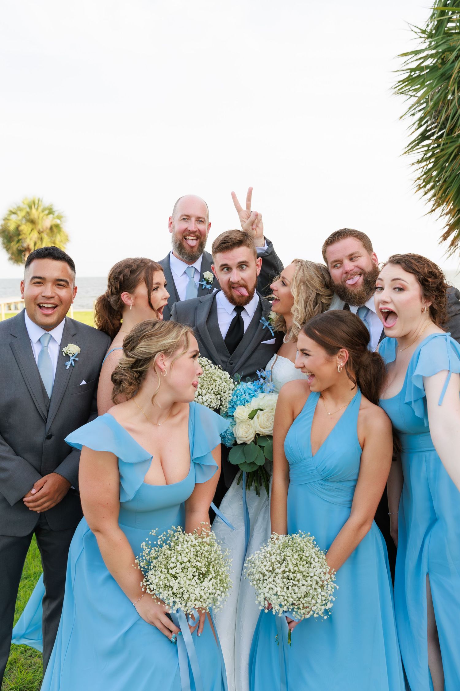 Candid moment of wedding party laughing and making faces during outdoor photo session.