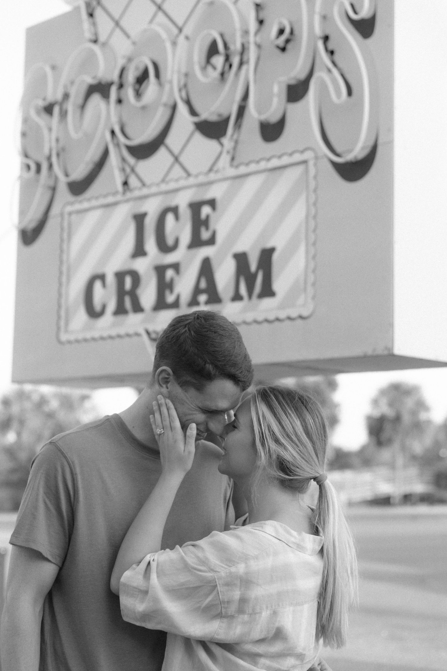 A tender moment captured in black and white beneath a vintage ice cream shop sign.