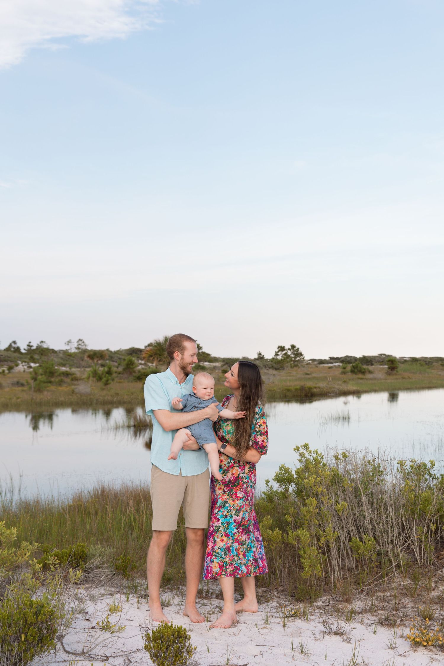 A family shares an intimate moment together by a coastal lake at sunset.