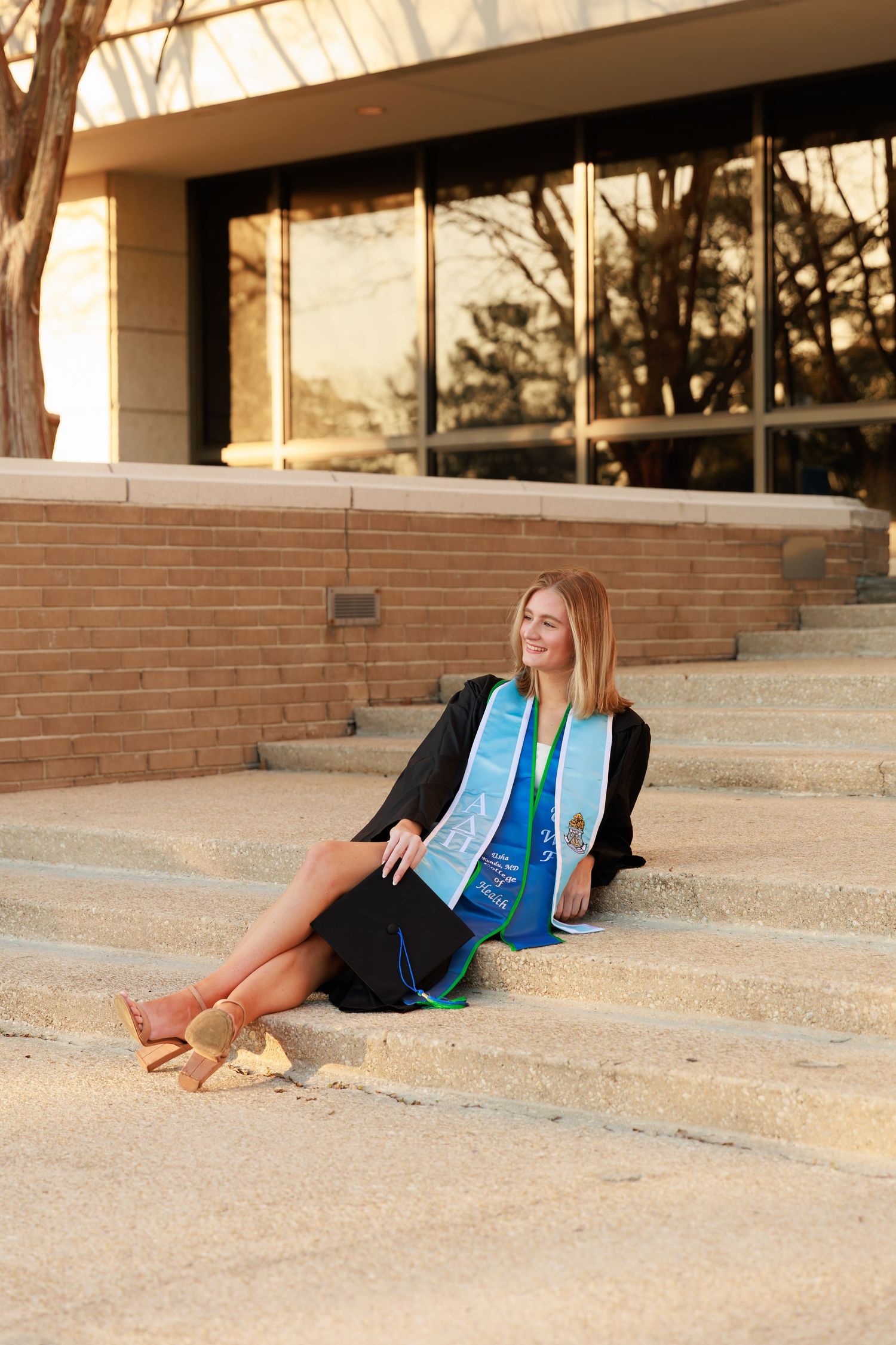A person in a blue and white vest lies on concrete steps in an outdoor setting during golden hour lighting.