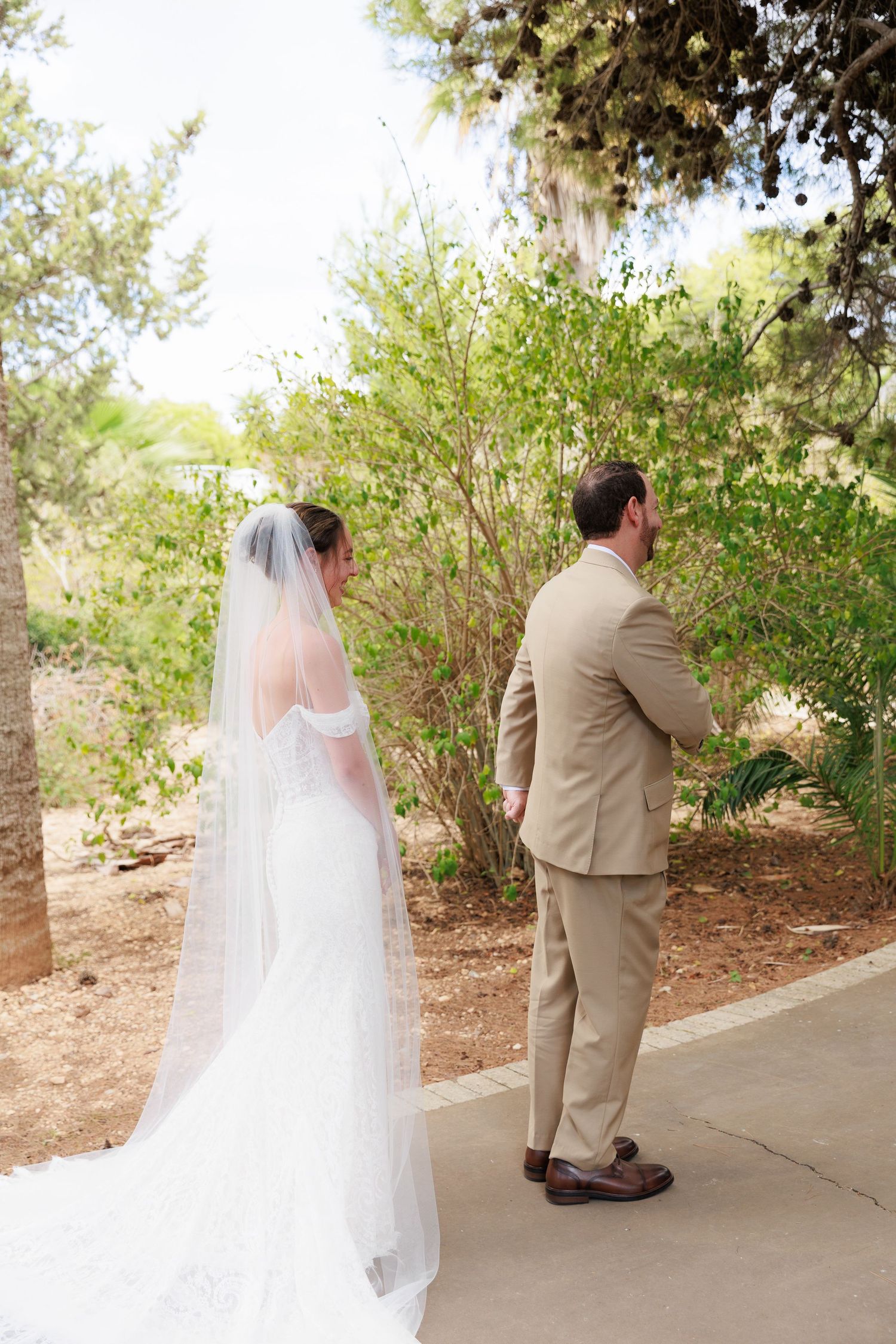 A series of wedding photos showing a bride in a white gown and veil with a groom in a tan suit on a garden path.