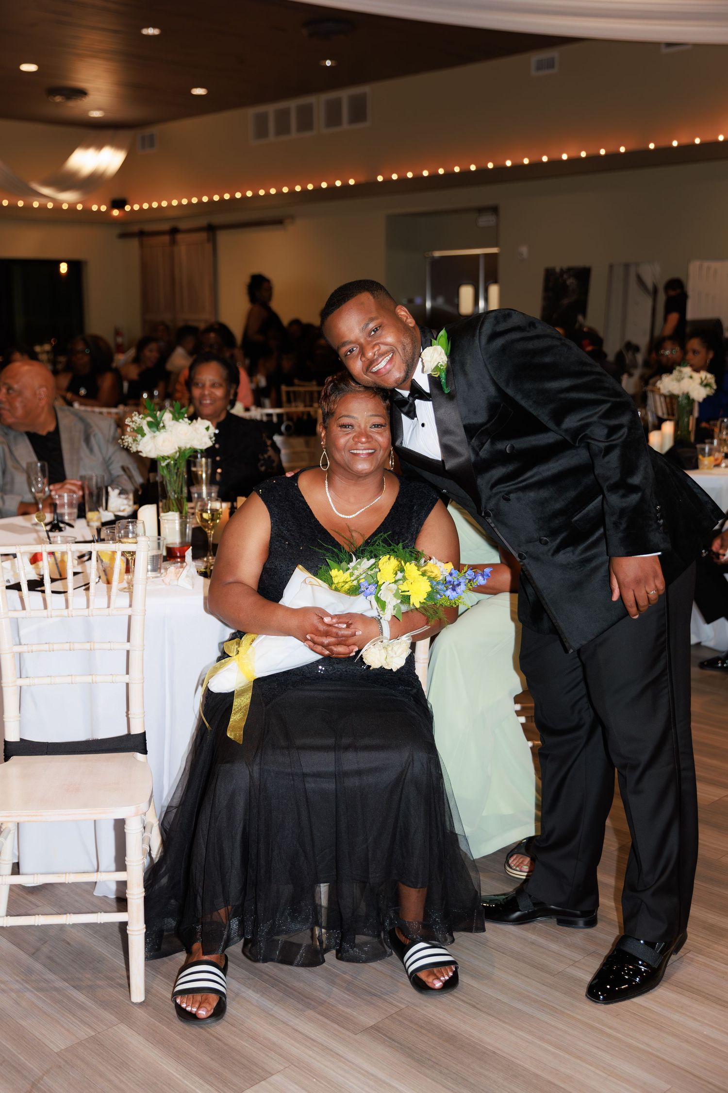 Wedding celebration with guests dancing and mingling in an elegantly lit reception hall.