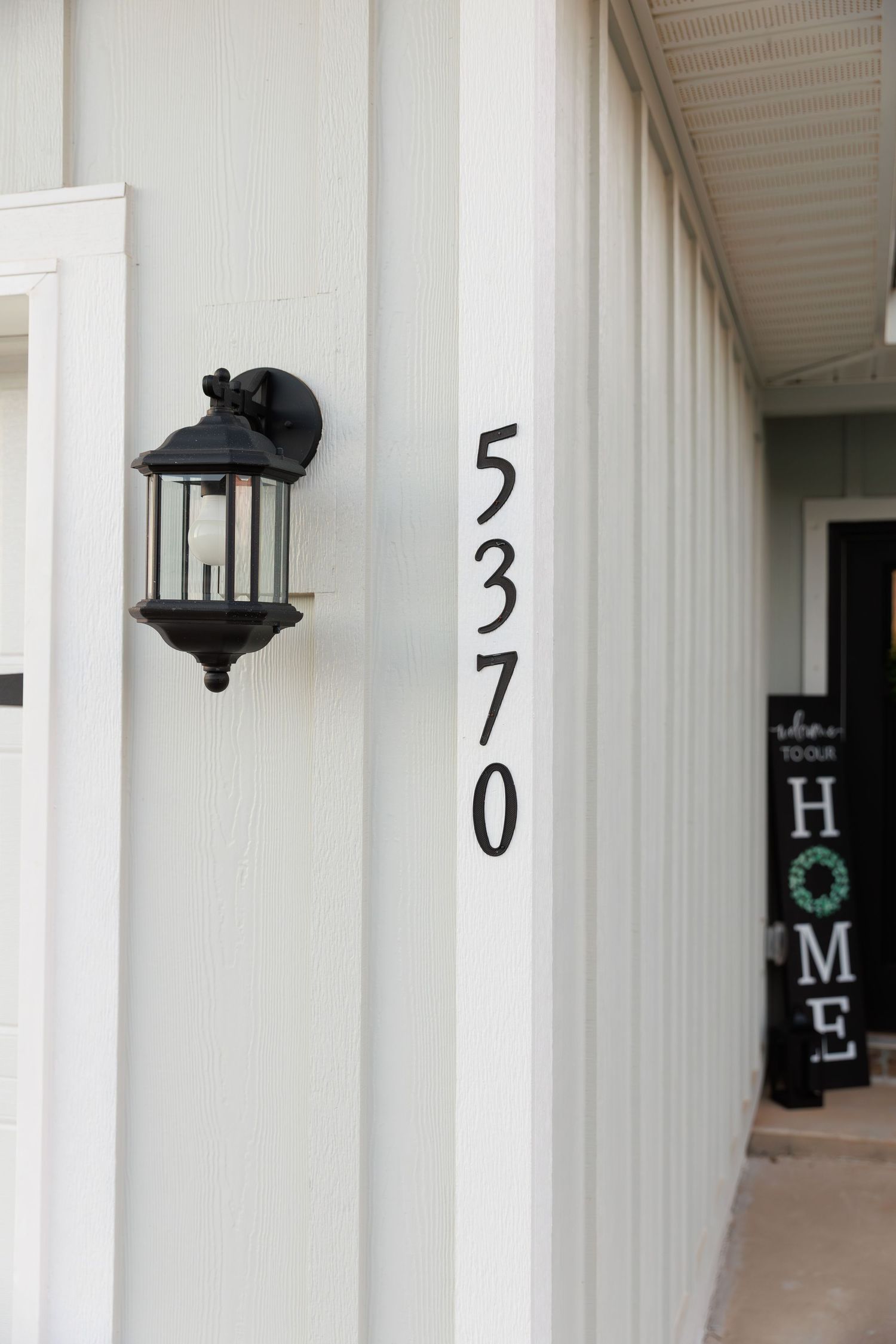 White apartment building hallway with numbered doors and a black decorative wreath visible in the distance.
